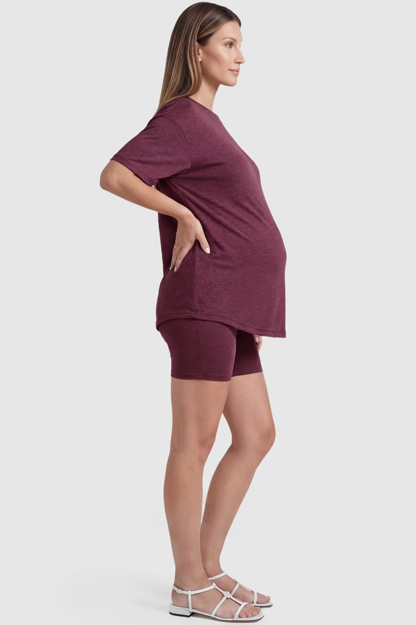 Stretch Oversized Tee & Biker Short Maternity Lounge Set in burgundy featuring a loose-fit tee and flexible waistband shorts on a pregnant model, side view.
