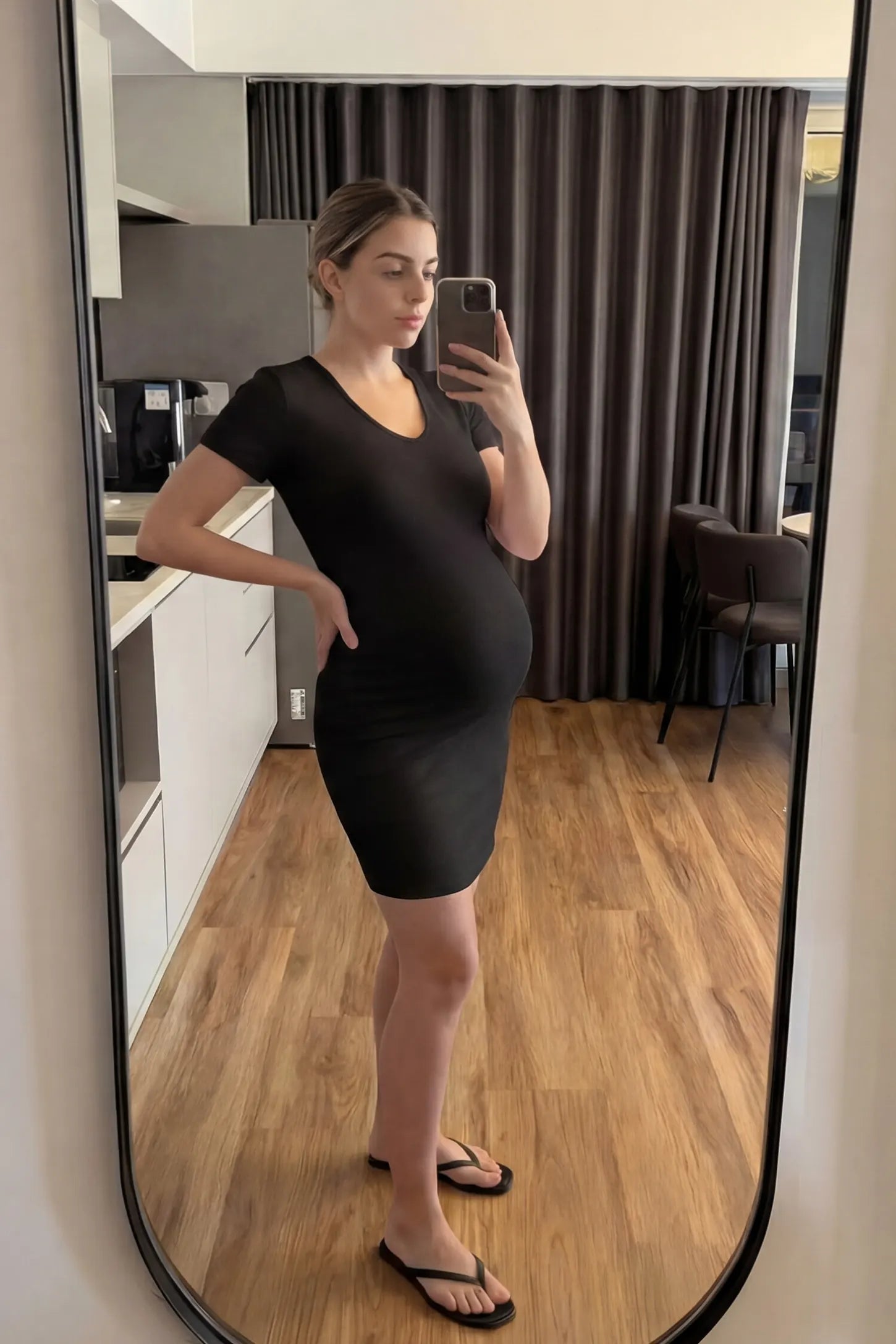 Stretchy Ribbed Short Sleeve Maternity Bodycon Dress UGC: Stretchy Ribbed Short Sleeve Maternity Bodycon Dress in Black featuring a stretchy V-neck ribbed design on a pregnant model, mirror selfie view.