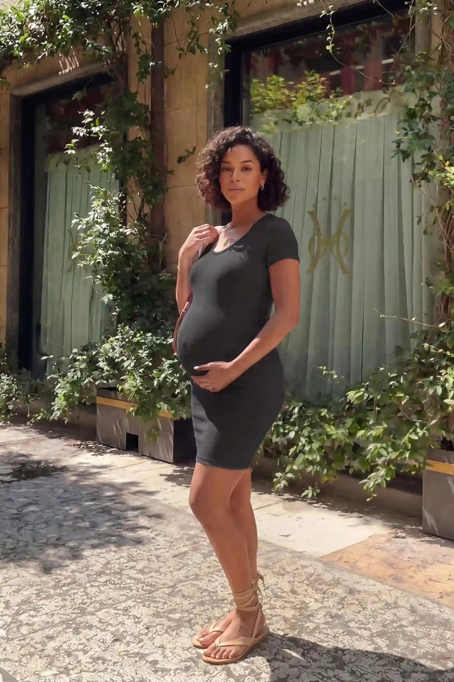 Stretchy Ribbed Short Sleeve Maternity Bodycon Dress Editorial Lifestyle: Stretchy Ribbed Short Sleeve Maternity Bodycon Dress in Dark Grey featuring a soft ribbed stretch fabric on a pregnant model, outdoor lifestyle view.