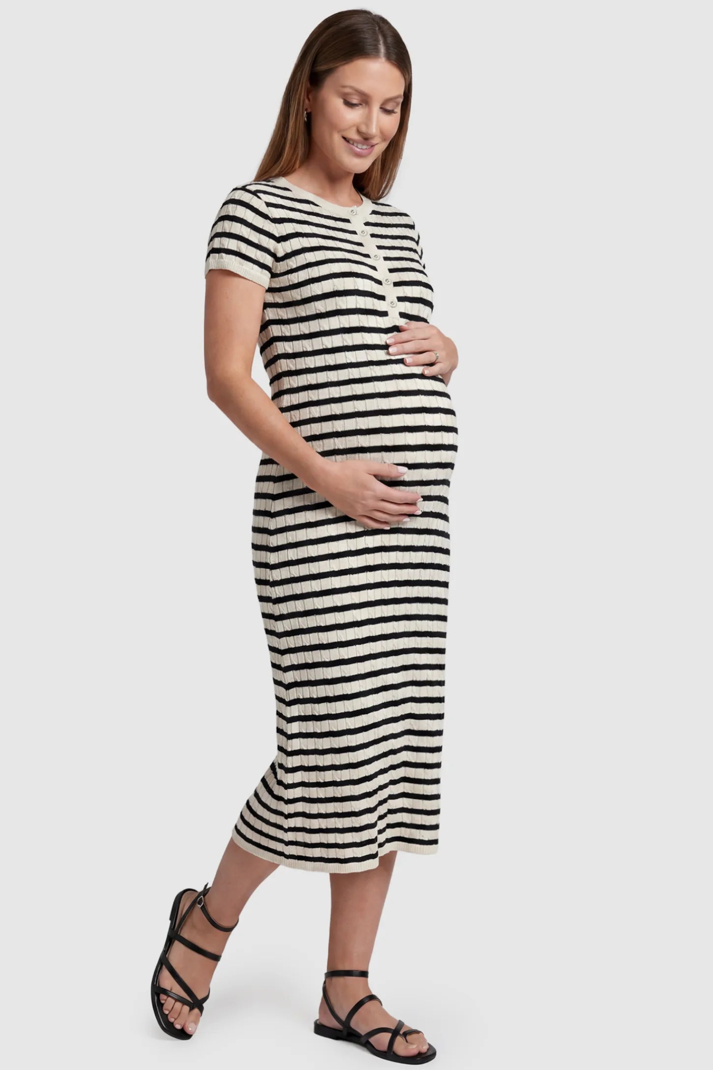 Striped Button Front Short Sleeve Maternity Midi Dress Striped Button Front Short Sleeve Maternity Midi Dress in black stripe featuring short sleeves and a round neck on a pregnant model, side view.