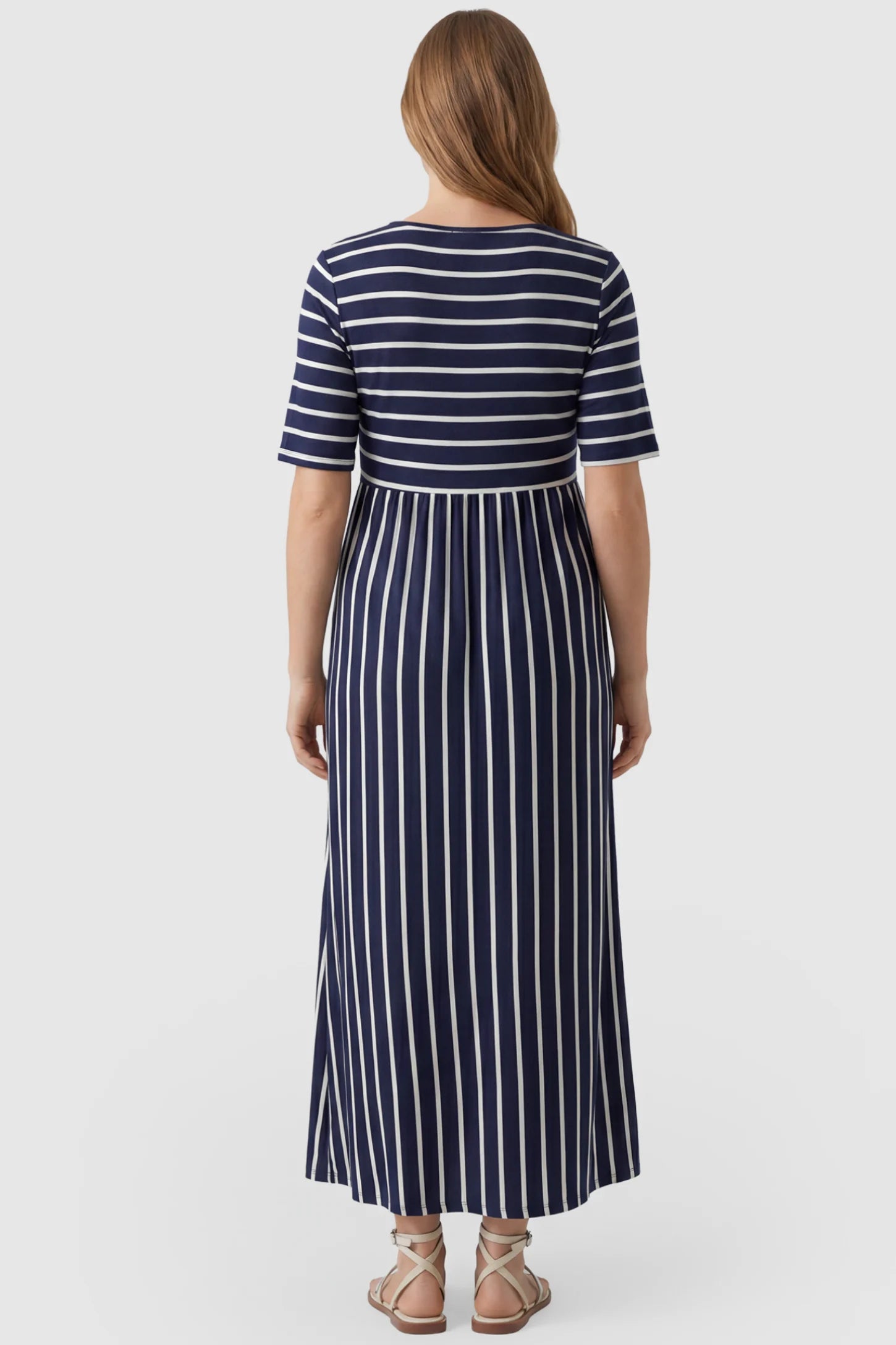 Striped Long Sleeve Maternity Maxi Dress Stretch Jersey Mixed-Stripe Maternity Maxi Dress in dark blue and White featuring an empire waist on a pregnant model, back view.