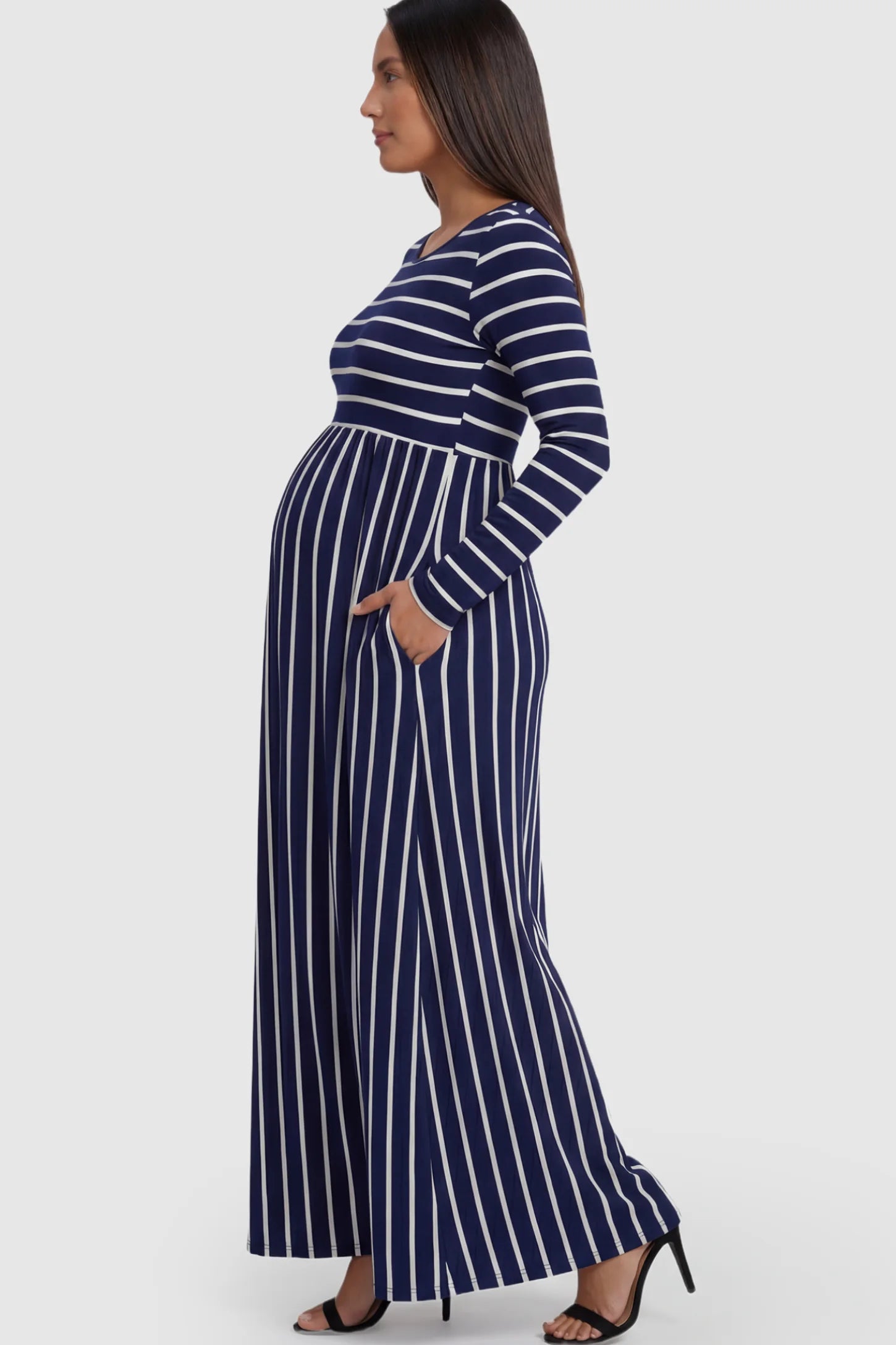 Striped Long Sleeve Maternity Maxi Dress Stretch Jersey Mixed-Stripe Maternity Maxi Dress in dark blue and White featuring an empire waist on a pregnant model showing side.