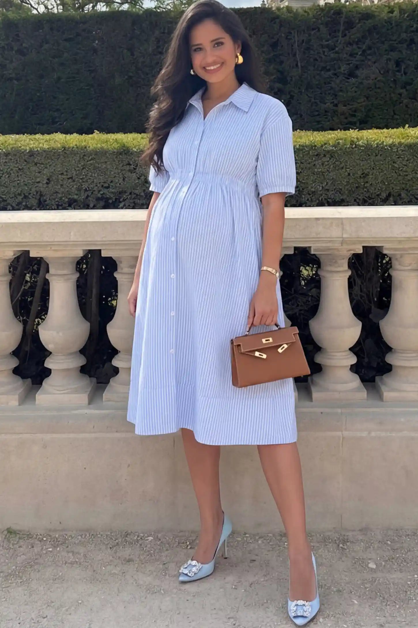 Striped Smocked Waist Button Down Maternity Shirt Dress Striped Smocked-Waist Button-Down Maternity Shirt Dress in light blue and white stripes featuring a collared neckline and short sleeves on a pregnant woman.