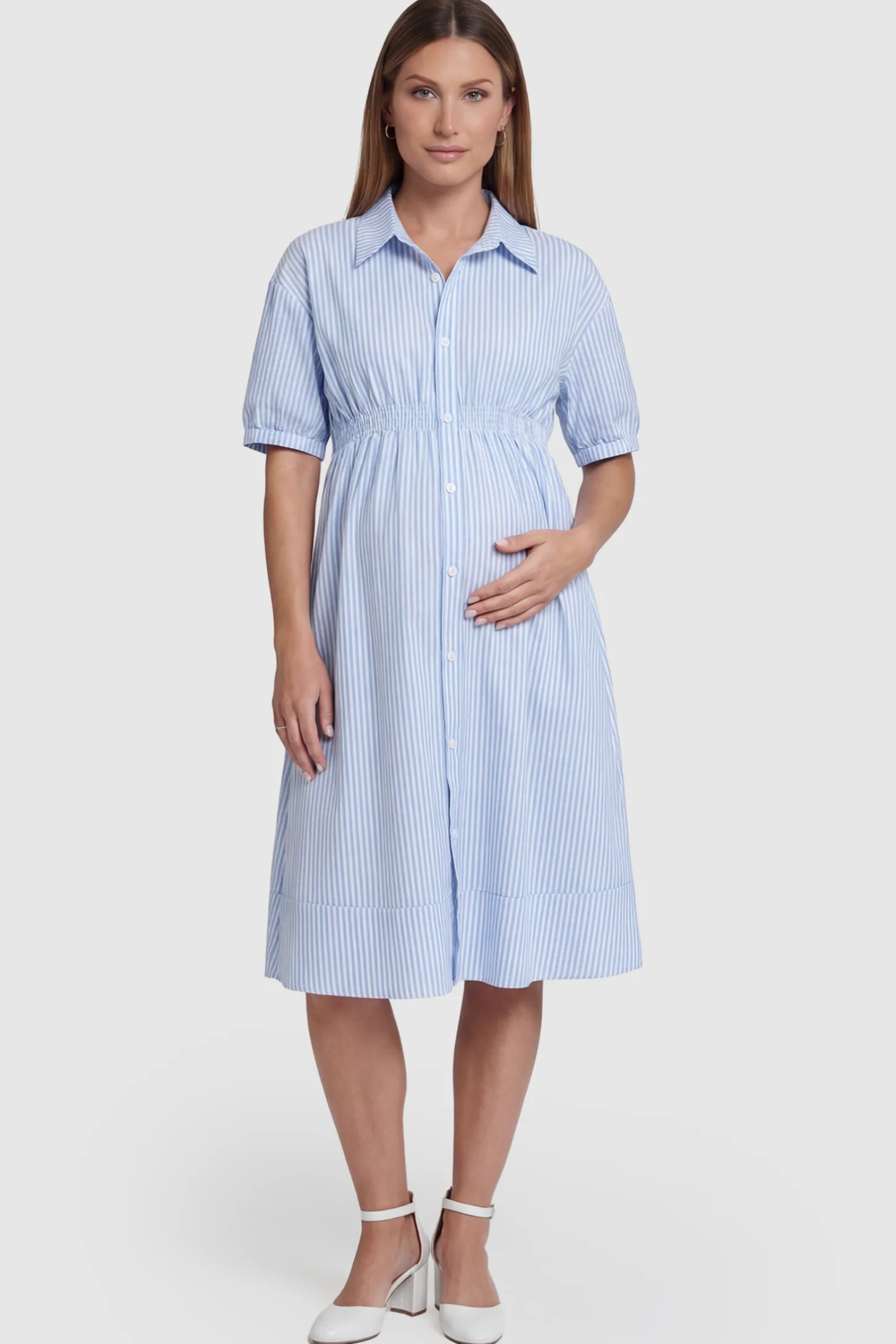 Striped Smocked-Waist Button-Down Maternity Shirt Dress in light blue and white stripes featuring a collared neckline and short sleeves on a pregnant model posing front.