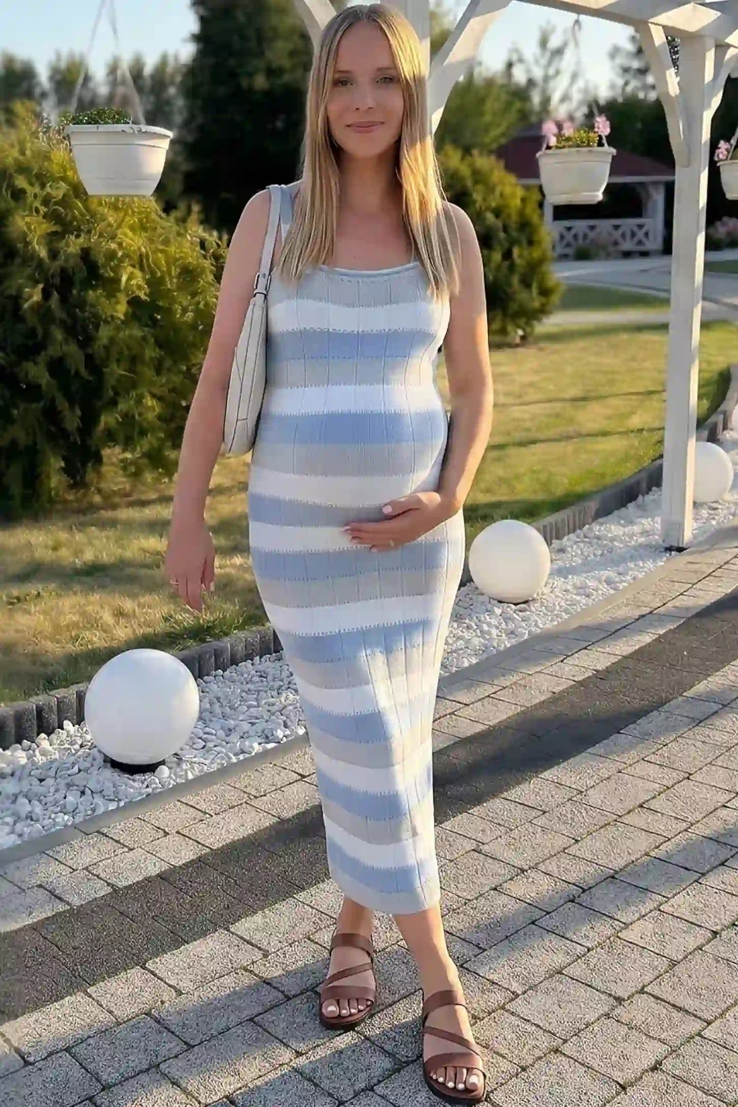 Striped Square Neck Sleeveless Maternity Midi Dress Striped Square Neck Sleeveless Maternity Midi Dress in Blue featuring adjustable slider straps and soft knit stretch on a pregnant model in outdoor setting, front view.