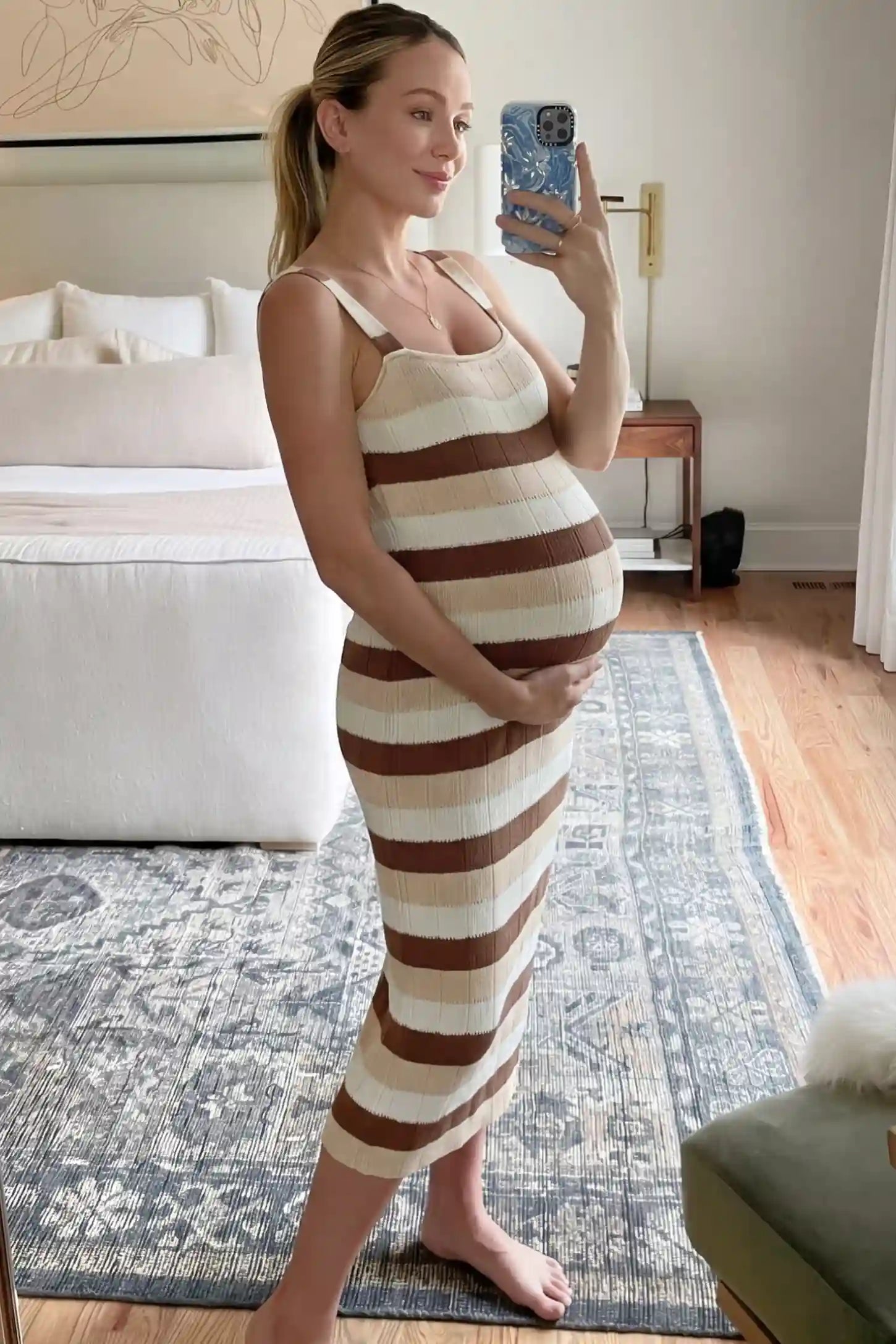 Striped Square Neck Sleeveless Maternity Midi Dress Striped Square Neck Sleeveless Maternity Midi Dress in Brown featuring adjustable slider straps and soft knit stretch on a pregnant model in indoor setting, side view.