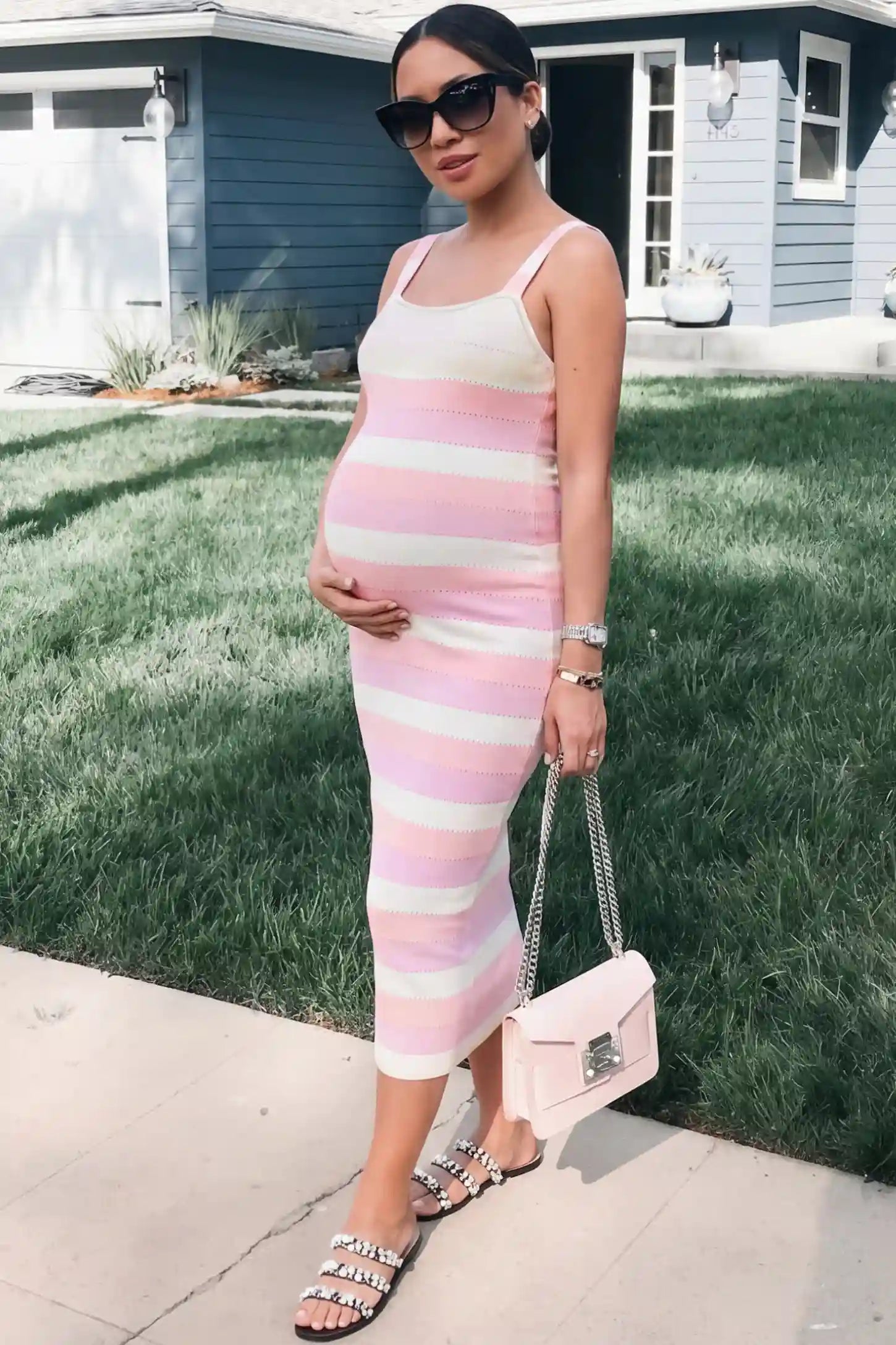 Striped Square Neck Sleeveless Maternity Midi Dress Striped Square Neck Sleeveless Maternity Midi Dress in Pink featuring adjustable slider straps and soft knit stretch on a pregnant model in outdoor setting, side view.