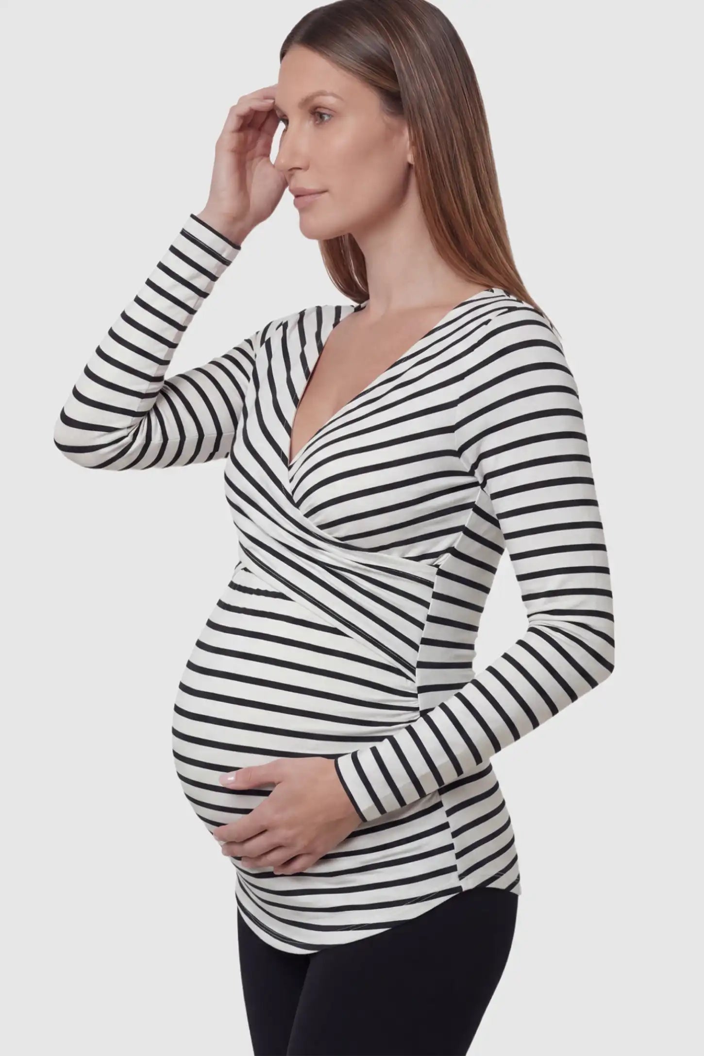 Striped Wrap Front Maternity & Nursing Top Striped Wrap Front Nursing Top in white with crossover neckline on a pregnant model showing side.