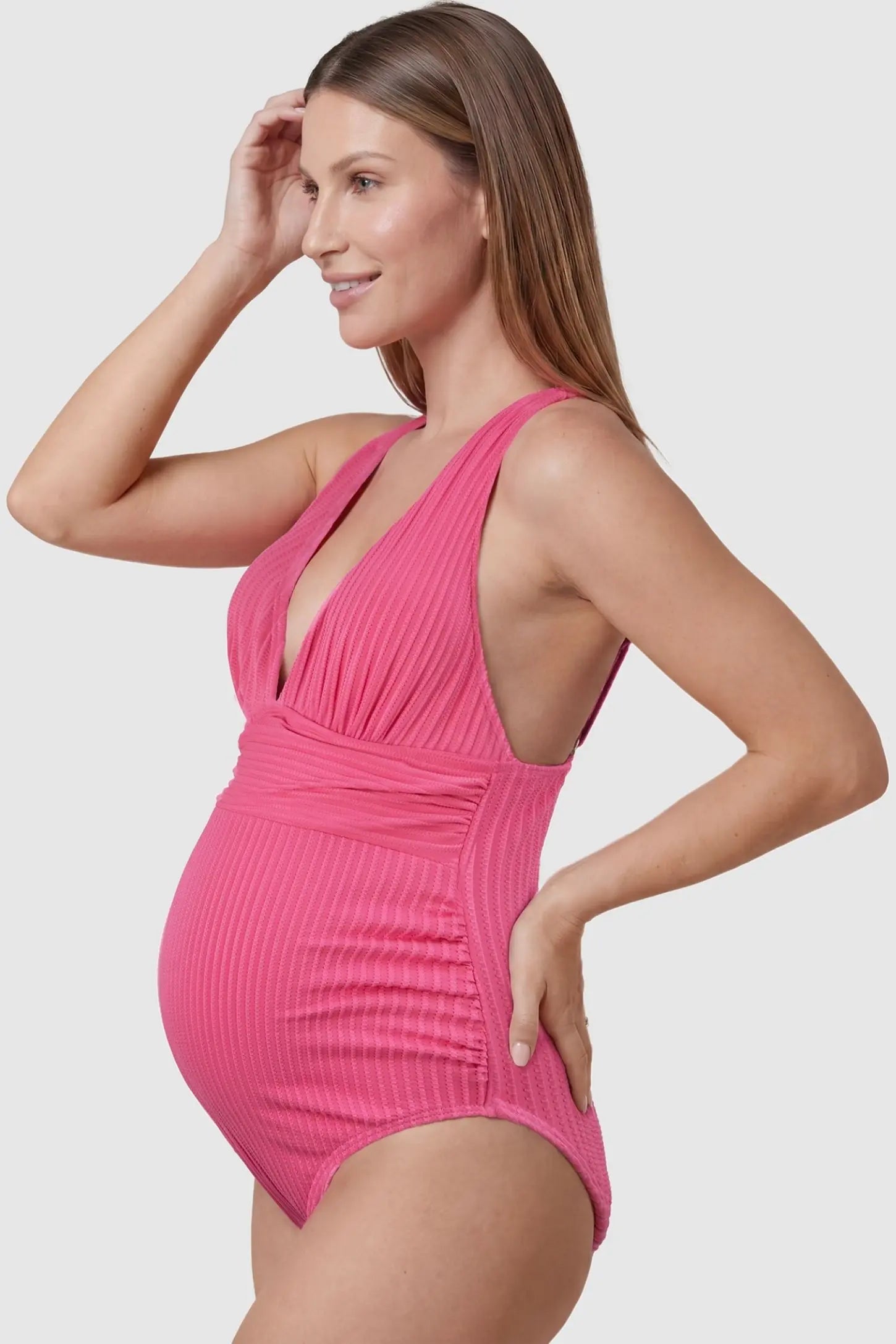 Textured Curve-Hugging Maternity One Piece Swimsuit Textured Curve-Hugging One Piece Swimsuit in Pink featuring a textured ribbed finish on a pregnant model, side view.
