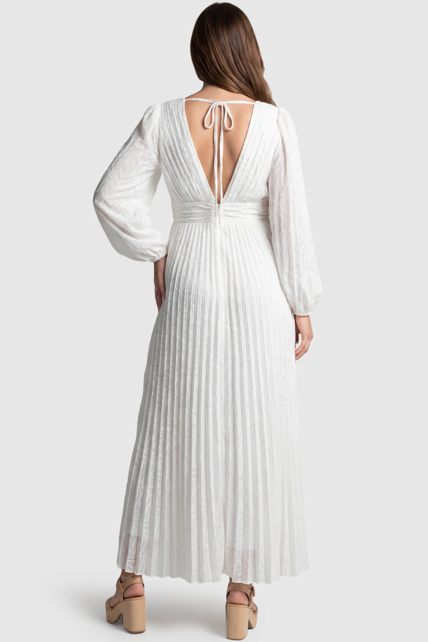Textured Empire Waist Long Sleeve Maternity Maxi Dress Textured Empire Waist Long Sleeve Maternity Maxi Dress in White featuring a deep V-back with tie detail on a pregnant model back view.