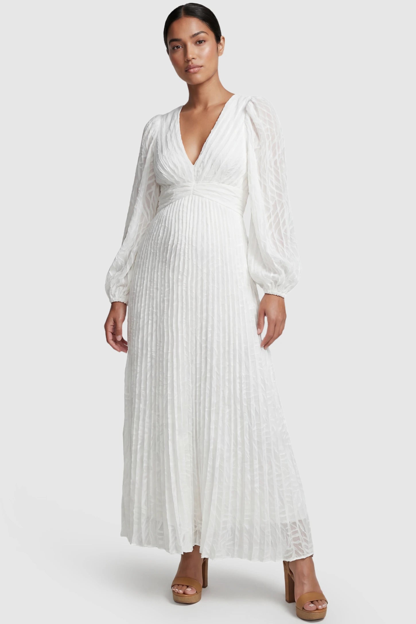 Textured Empire Waist Long Sleeve Maternity Maxi Dress Textured Empire Waist Long Sleeve Maternity Maxi Dress in White featuring a V-neck and pleated skirt on a postpartum model front view.