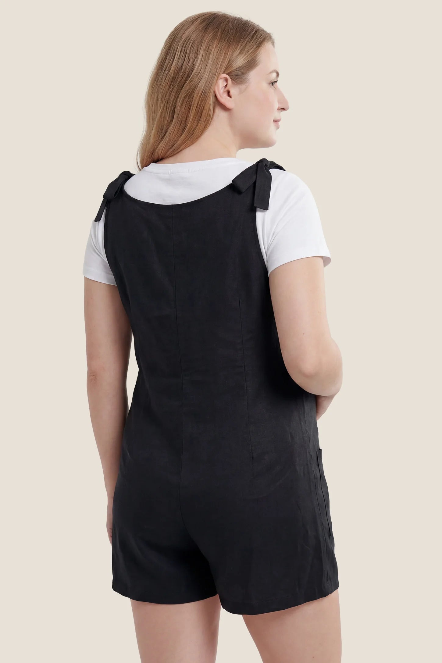 Tie-Strap Sleeveless Pocketed Maternity Romper Back view of the black Tie-Strap Sleeveless Pocketed Maternity Romper with tie shoulder straps and a relaxed fit.