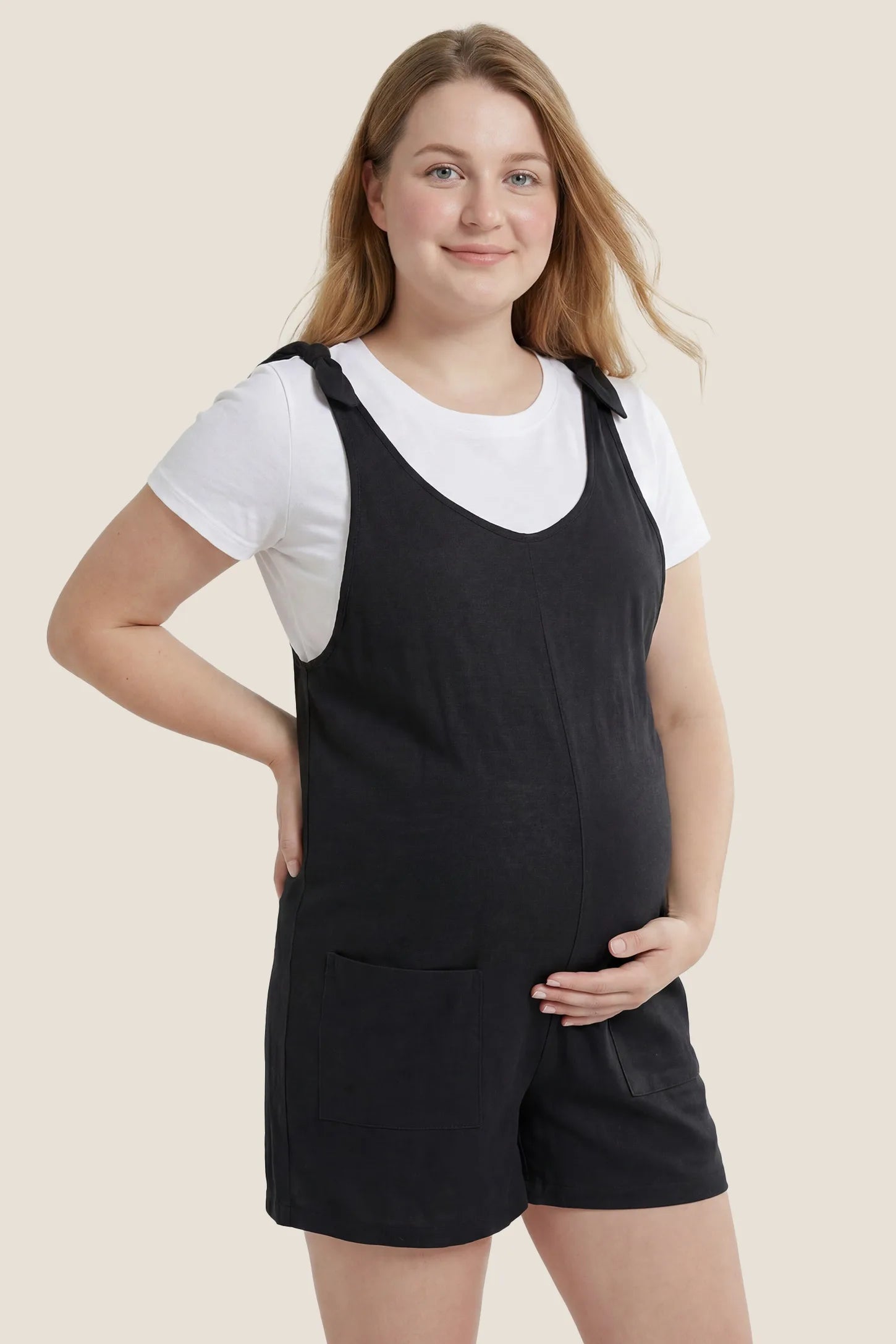 Side view of the black Tie-Strap Sleeveless Pocketed Maternity Romper designed for comfort throughout pregnancy and postpartum.