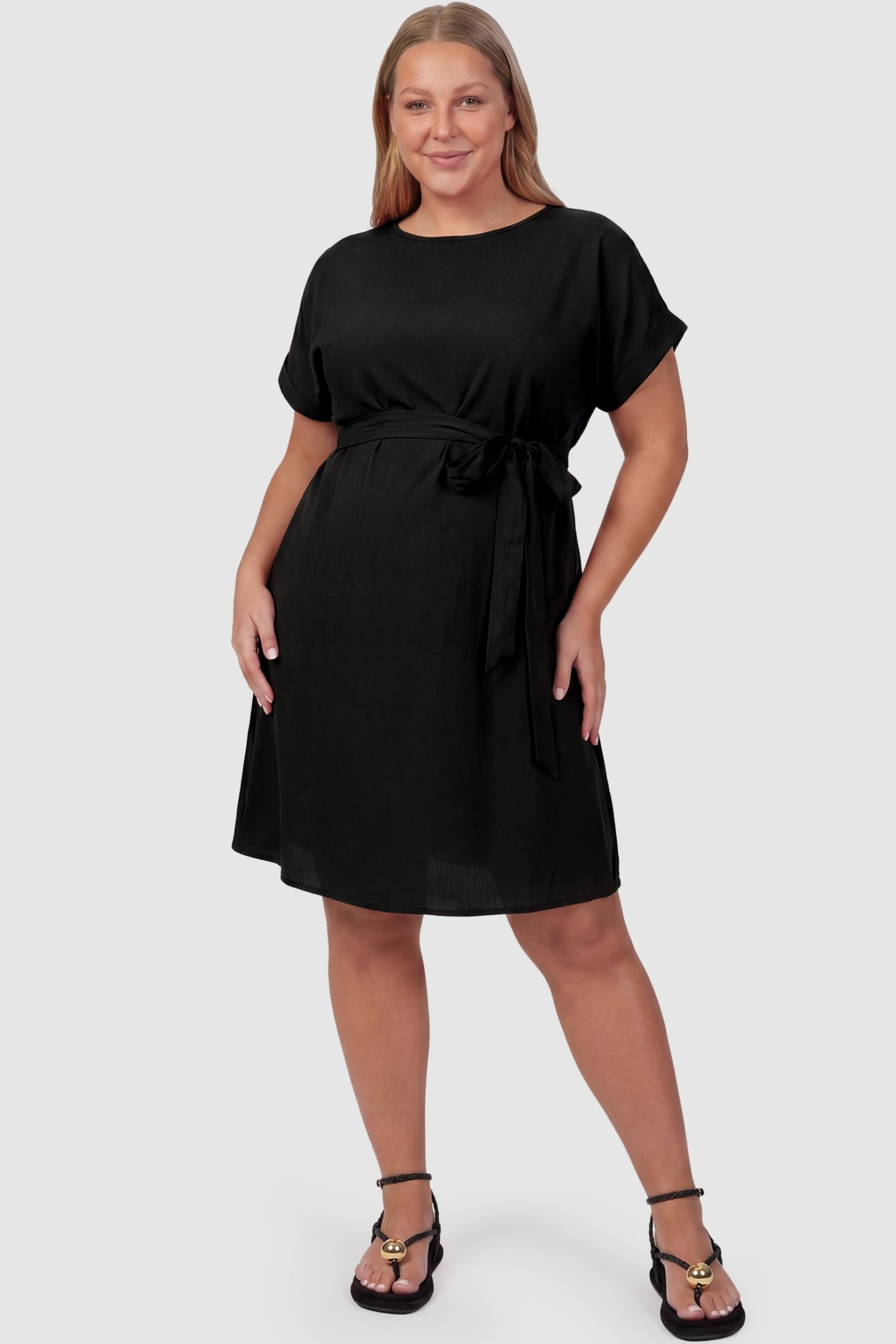 Lightweight Short Sleeve Tie Waist Flowy Maternity Mini Dress Lightweight Short Sleeve Tie Waist Flowy Maternity Mini Dress in Black featuring a relaxed empire waist tie on a plus size model, front view.
