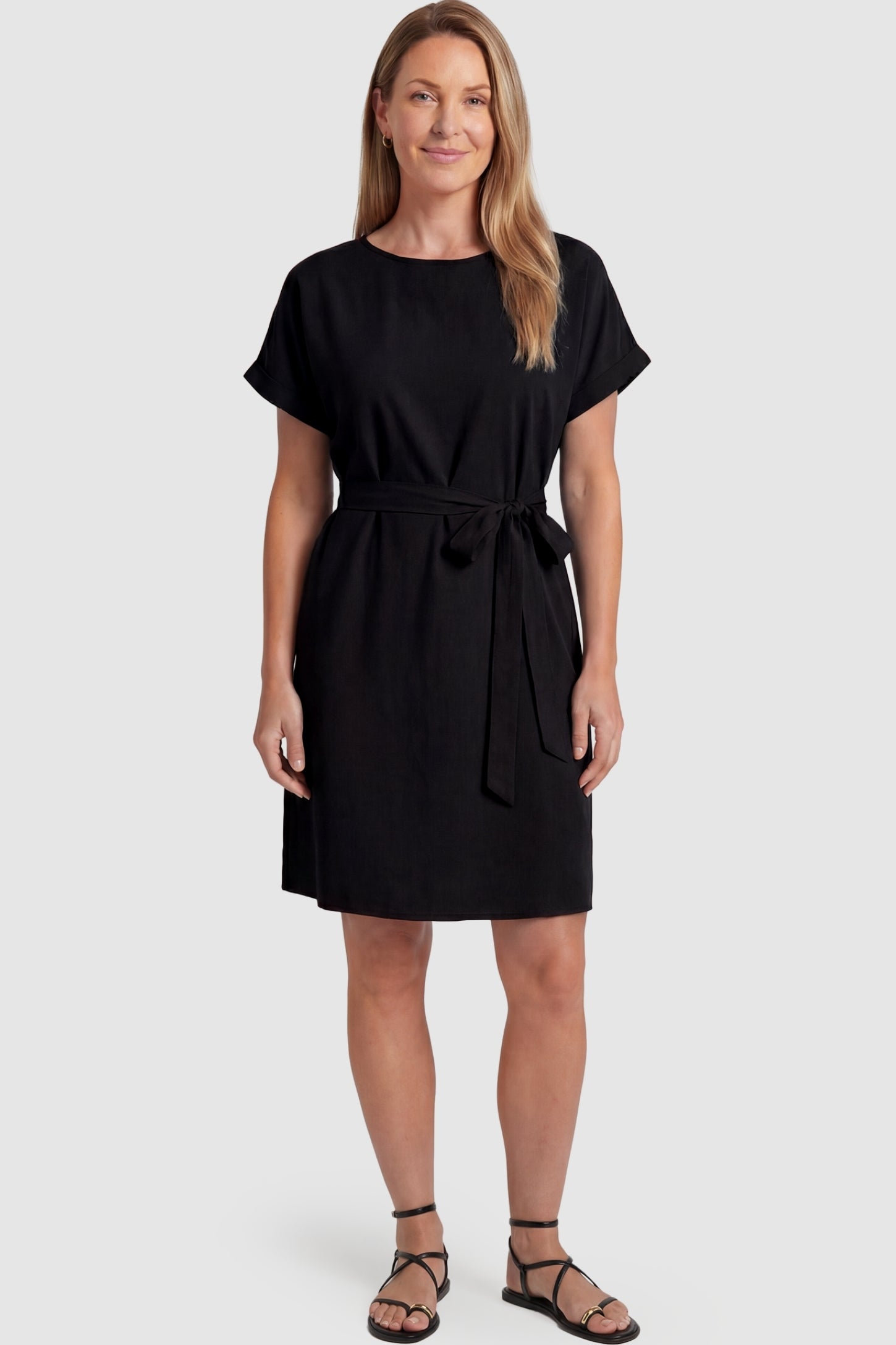 Lightweight Short Sleeve Tie Waist Flowy Maternity Mini Dress Lightweight Short Sleeve Tie Waist Flowy Maternity Mini Dress in Black featuring a relaxed empire waist tie on a non-pregnant model, postpartum view.