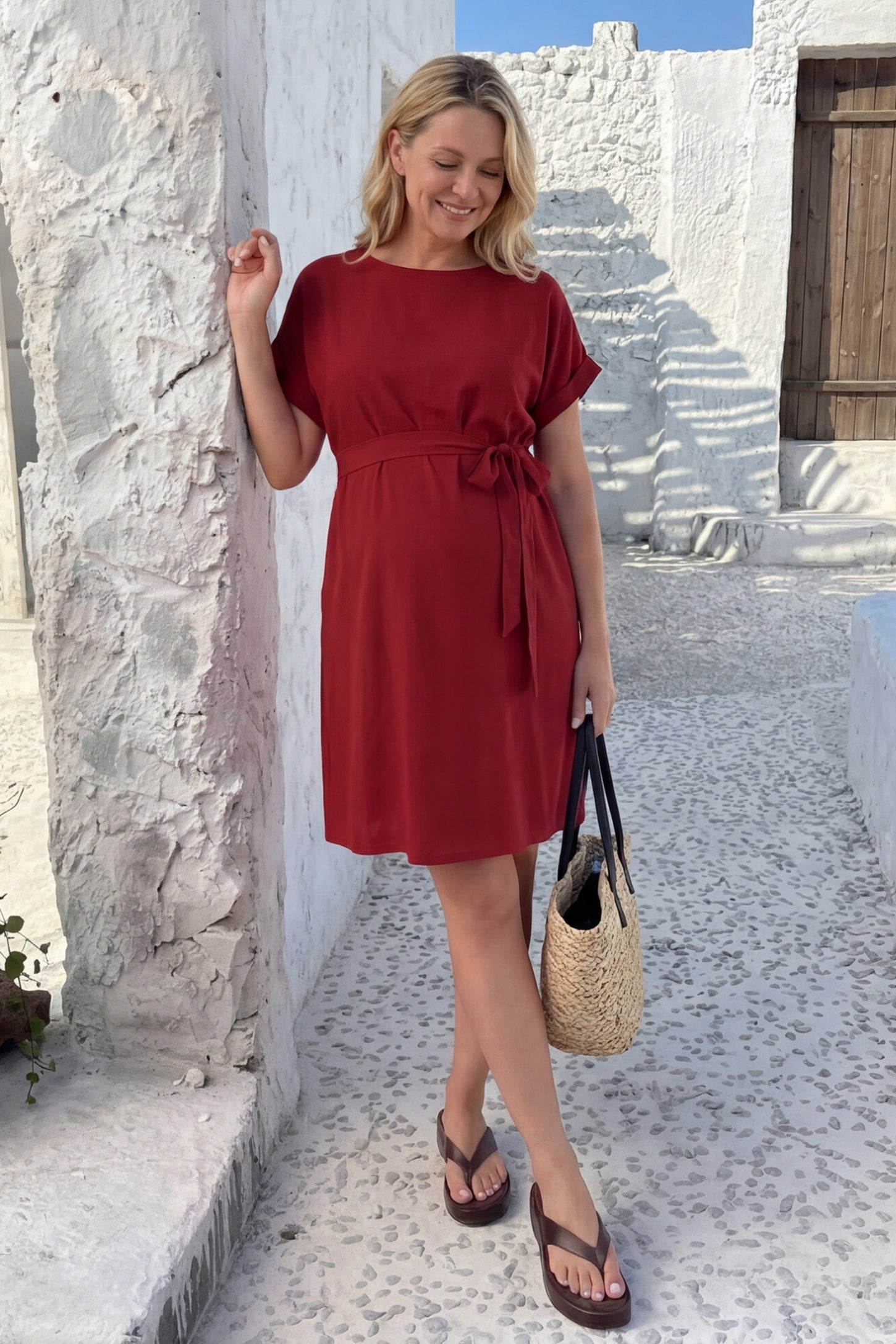 Lightweight Short Sleeve Tie Waist Flowy Maternity Mini Dress Lightweight Short Sleeve Tie Waist Flowy Maternity Mini Dress in Rust featuring a cuffed sleeve detail styled with sandals and a woven bag, editorial lifestyle view.