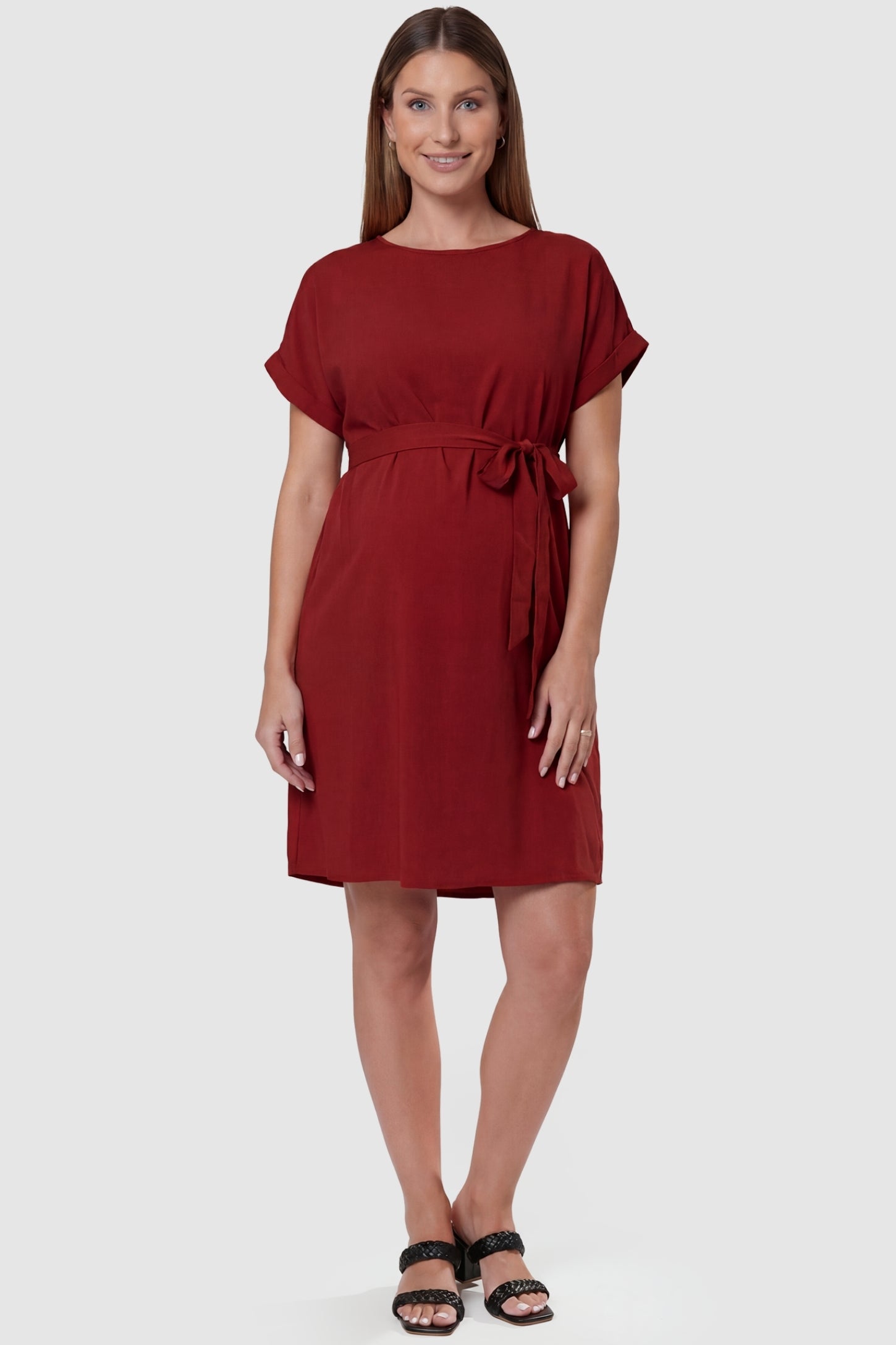 Lightweight Short Sleeve Tie Waist Flowy Maternity Mini Dress Lightweight Short Sleeve Tie Waist Flowy Maternity Mini Dress in Rust featuring a relaxed empire waist tie on a pregnant model, front view.