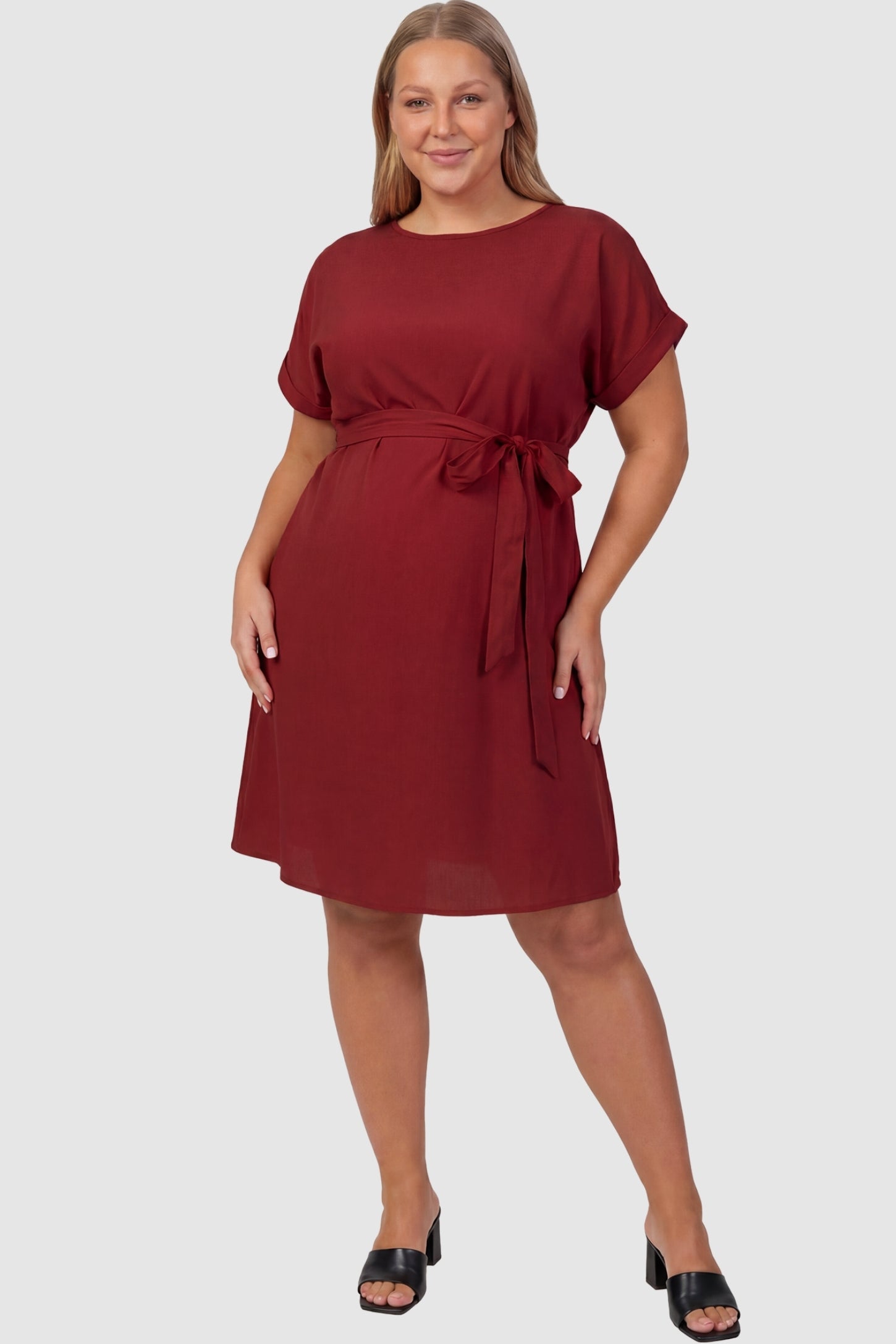 Lightweight Short Sleeve Tie Waist Flowy Maternity Mini Dress Lightweight Short Sleeve Tie Waist Flowy Maternity Mini Dress in Rust featuring a relaxed empire waist tie on a plus size model, front view.