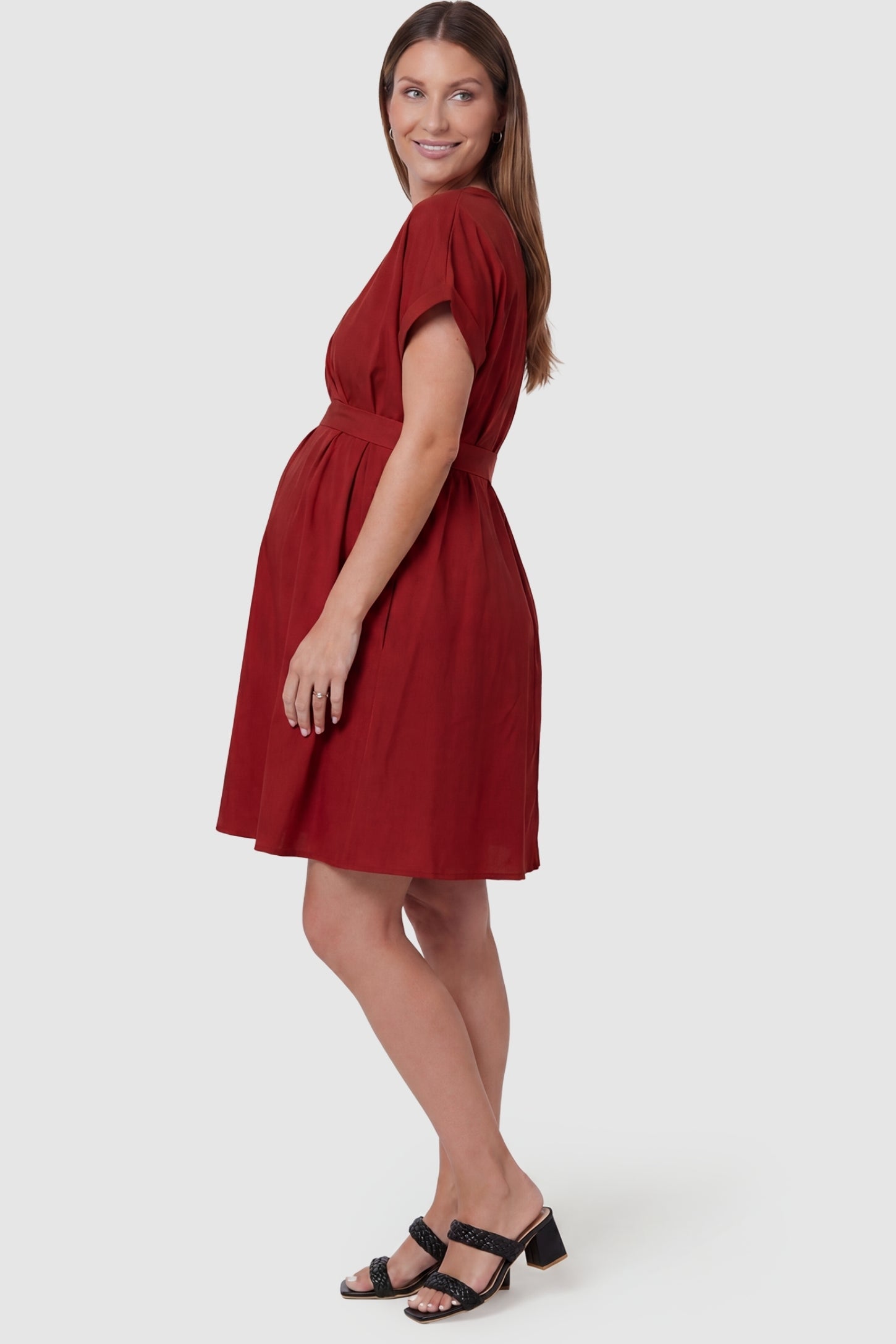 Lightweight Short Sleeve Tie Waist Flowy Maternity Mini Dress Lightweight Short Sleeve Tie Waist Flowy Maternity Mini Dress in Rust featuring a flowy gathered skirt on a pregnant model, side view.
