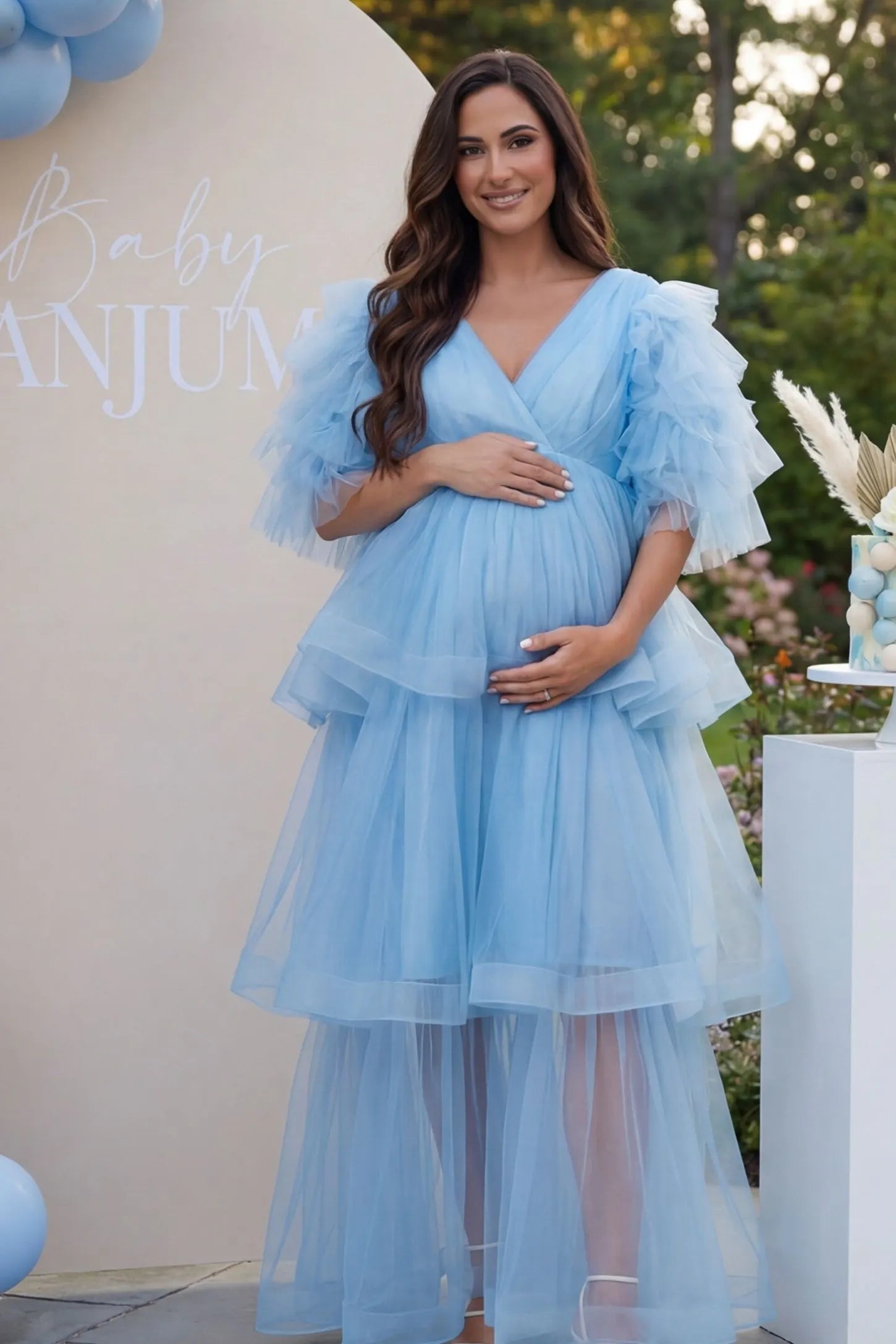 Tiered Ruffled Tulle Flutter Sleeve Maternity Maxi Gown in Blue with statement flutter sleeves on pregnant model at baby shower, front view.