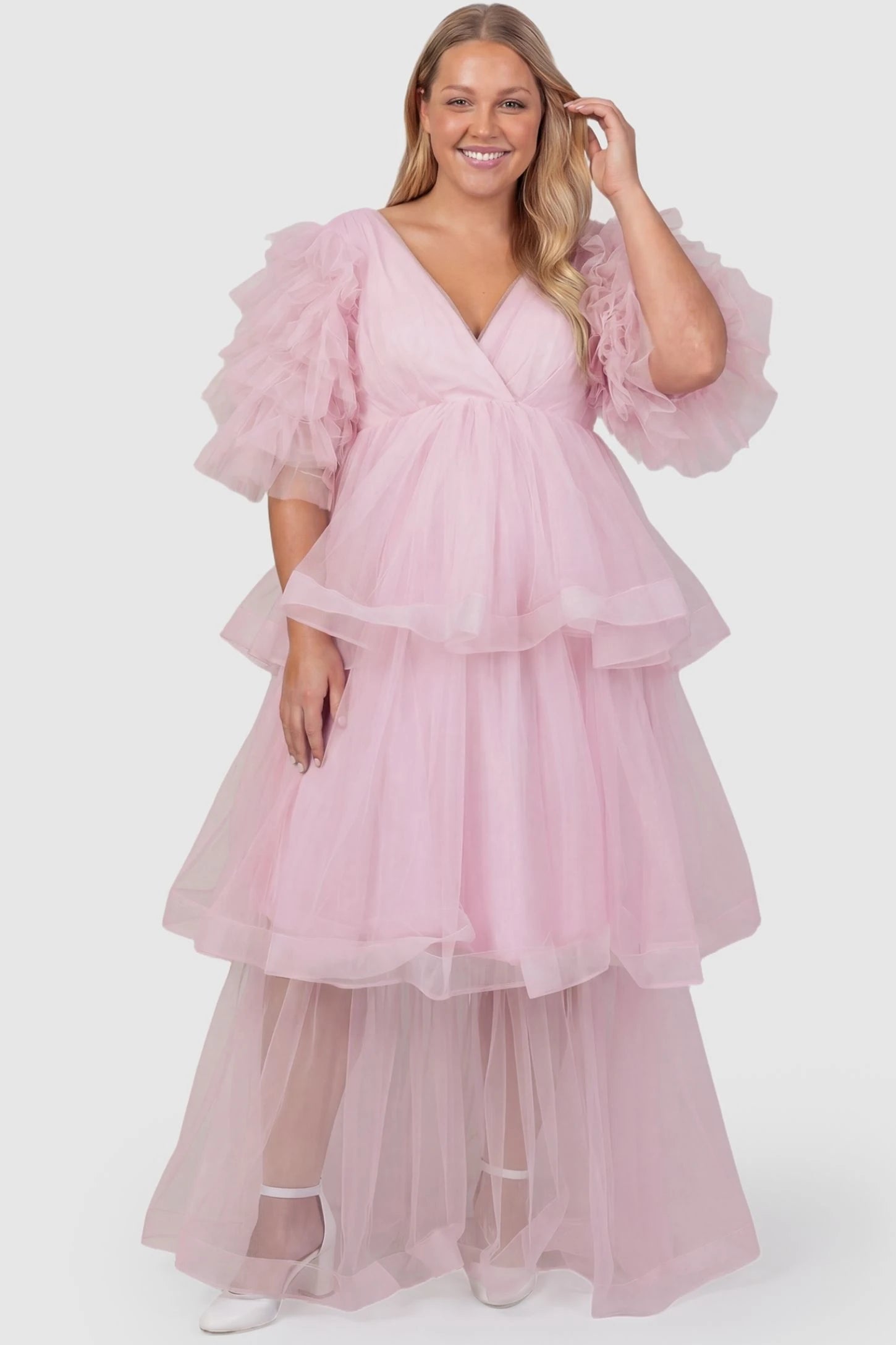 Tiered Ruffled Tulle Flutter Sleeve Maternity Maxi Gown Tiered Ruffled Tulle Flutter Sleeve Maternity Maxi Gown in Pink featuring ruffled flutter sleeves on plus size pregnant model, front view.