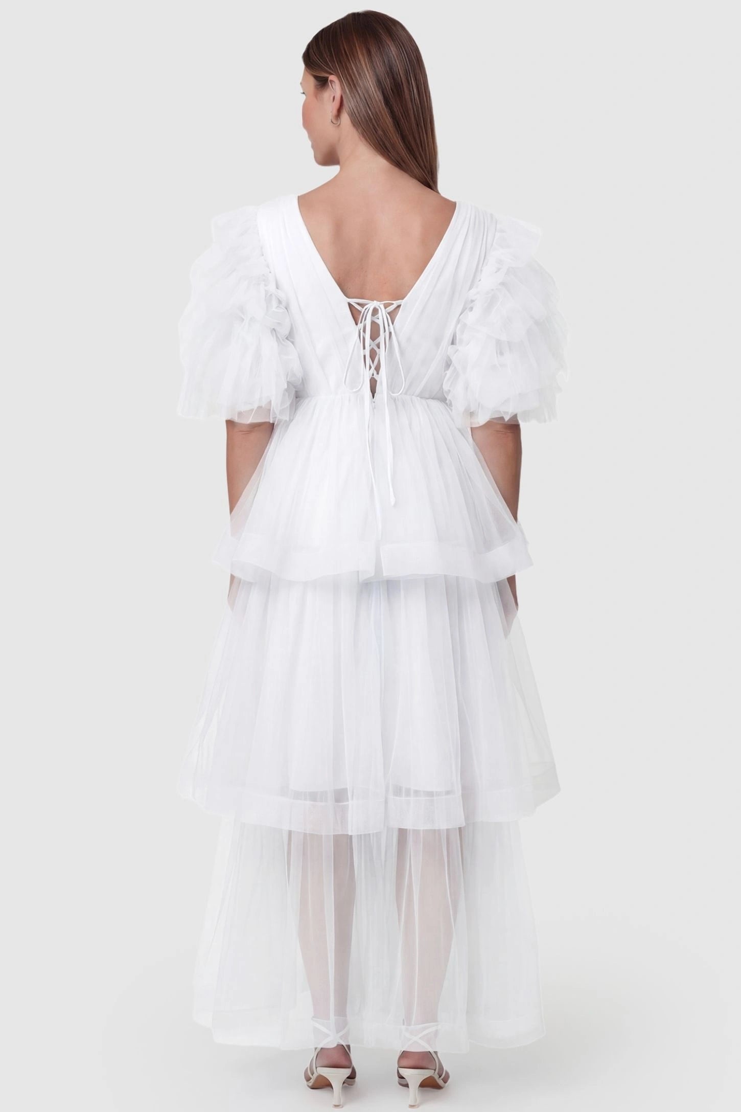 Tiered Ruffled Tulle Flutter Sleeve Maternity Maxi Gown Tiered Ruffled Tulle Flutter Sleeve Maternity Maxi Gown in White featuring lace-up back detail on pregnant model, back view.