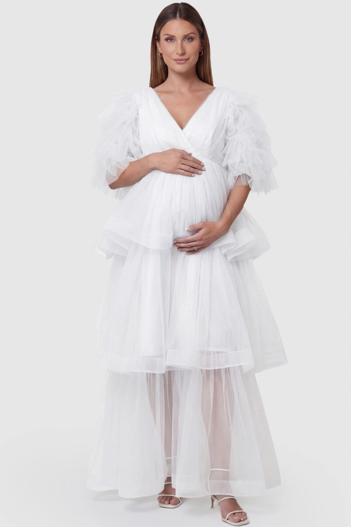 Tiered Ruffled Tulle Flutter Sleeve Maternity Maxi Gown Tiered Ruffled Tulle Flutter Sleeve Maternity Maxi Gown in White featuring layered tulle skirt on pregnant model, front view.