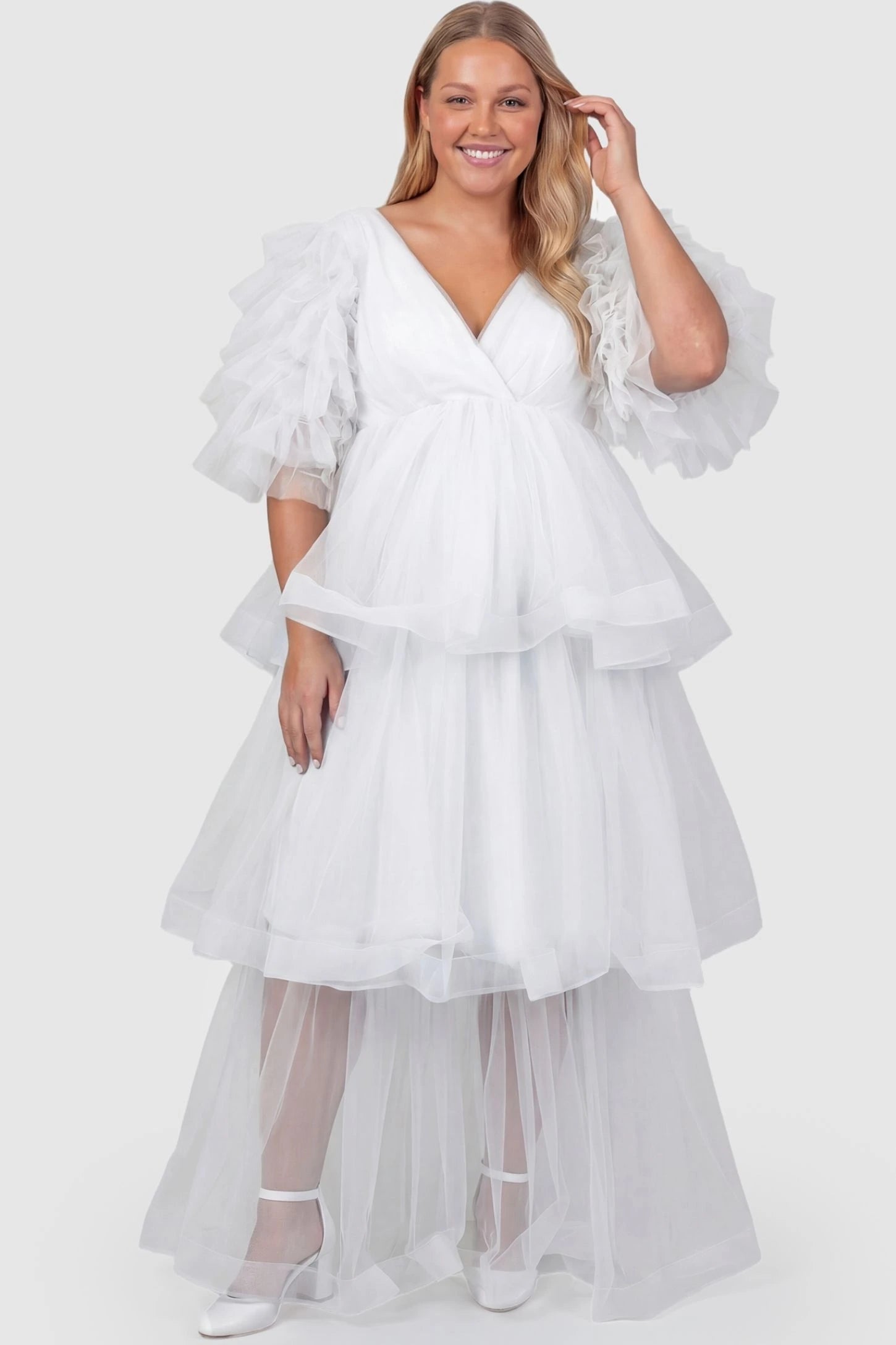 Tiered Ruffled Tulle Flutter Sleeve Maternity Maxi Gown Tiered Ruffled Tulle Flutter Sleeve Maternity Maxi Gown in White featuring ruffled flutter sleeves on plus size pregnant model, front view.
