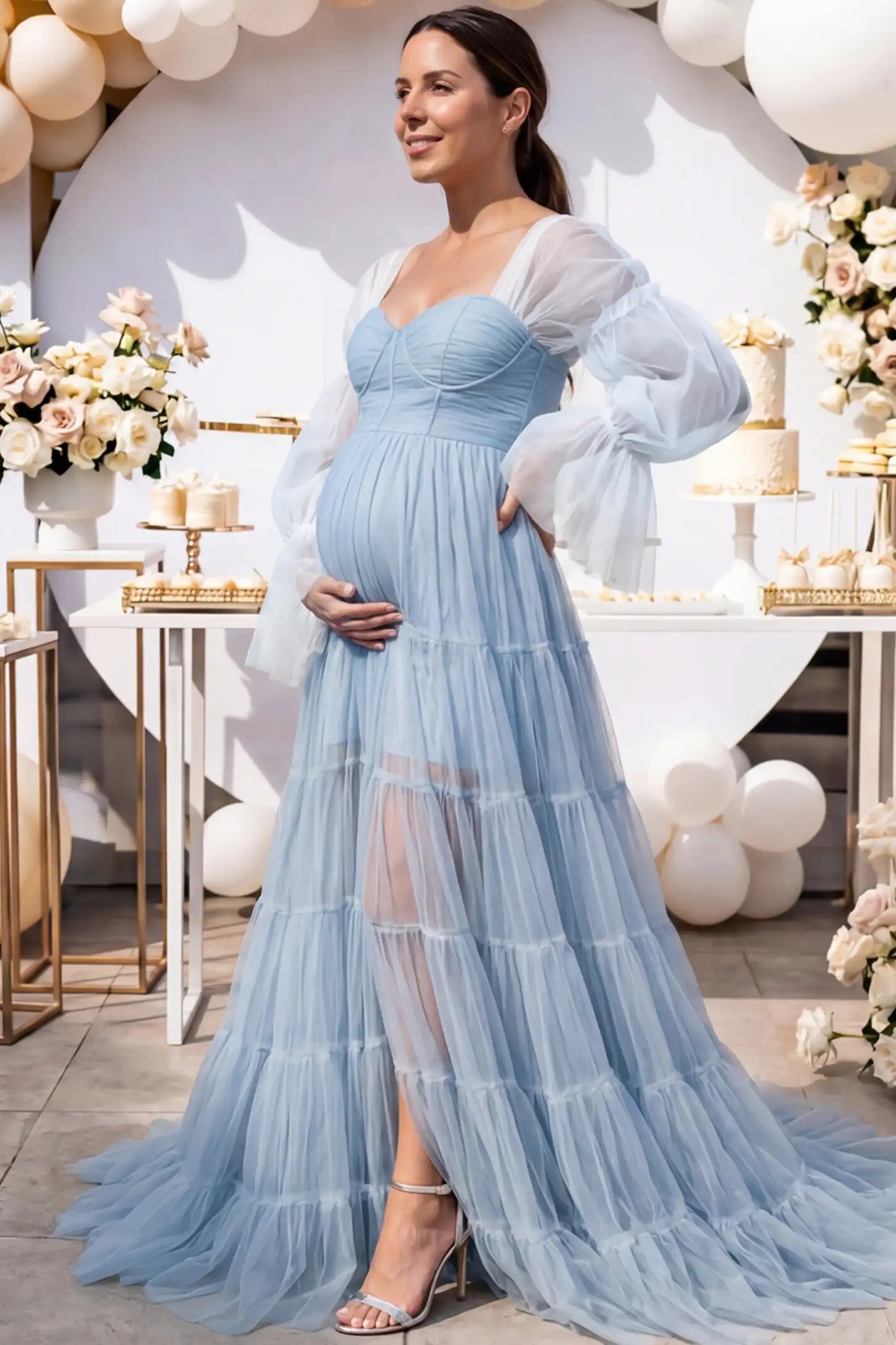 Tiered Tulle Long Sleeve Maternity Photoshoot Gown Tiered Tulle Long Sleeve Maternity photoshoot Gown in Blue featuring a sweetheart neckline and voluminous tulle layers on a pregnant woman in an outdoor setting, side view.
