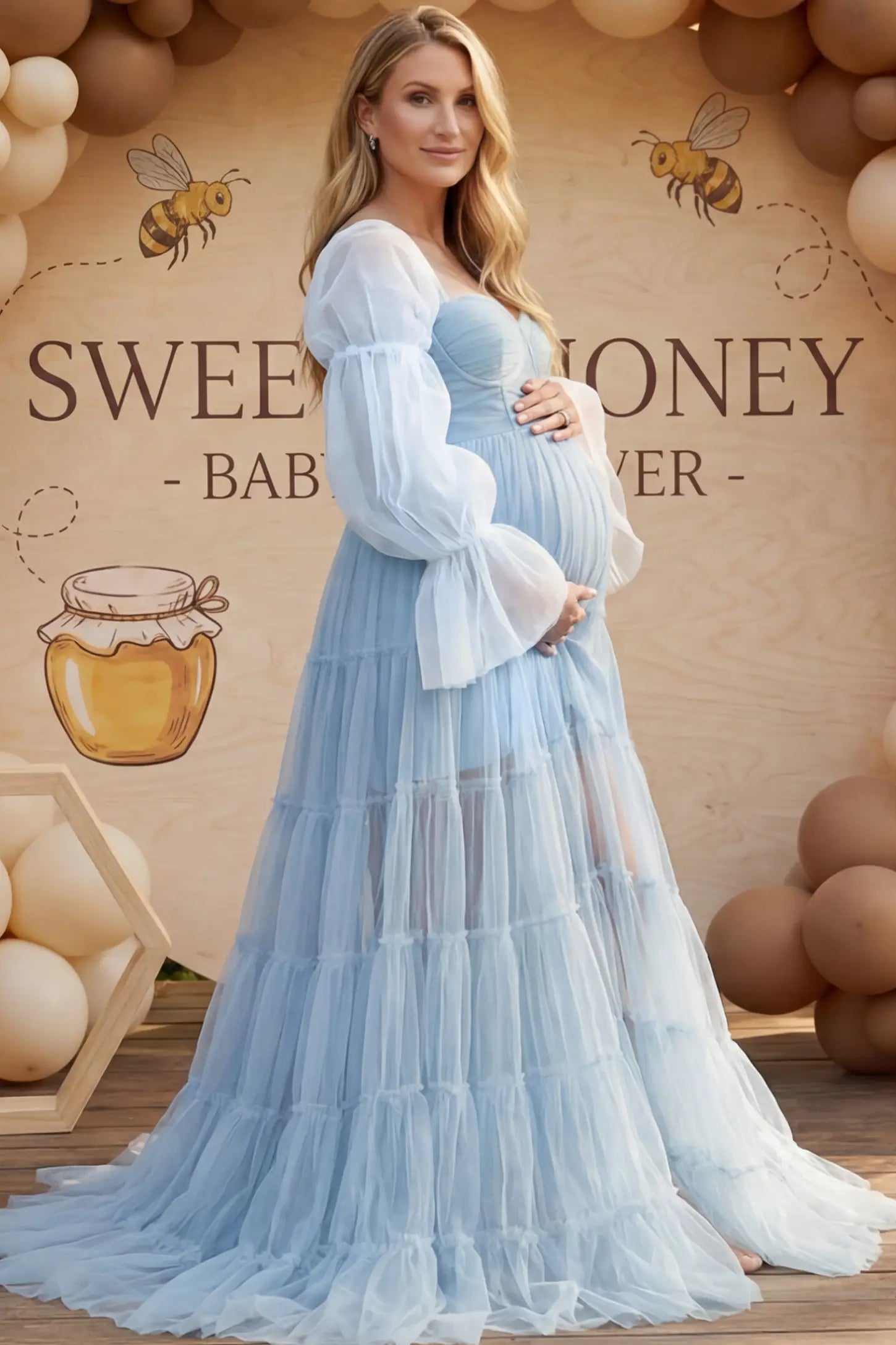 Tiered Tulle Long Sleeve Maternity Photoshoot Gown Tiered Tulle Long Sleeve Maternity photoshoot Gown in Blue featuring a sweetheart neckline and voluminous tulle layers on a pregnant woman in an outdoor setting, side view.