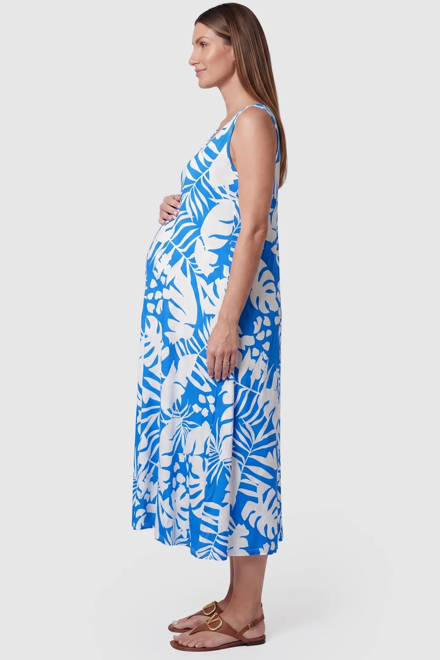 Tropical Print Sleeveless Midi Maternity Dress Tropical Print Sleeveless Midi Maternity Dress in Blue featuring a bump-friendly relaxed fit on a pregnant model, side view.