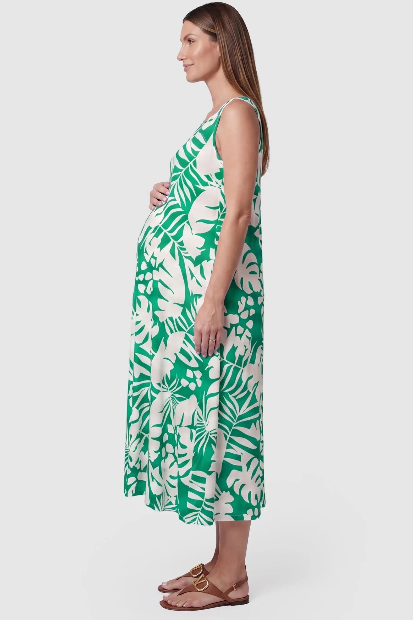 Tropical Print Sleeveless Midi Maternity Dress Tropical Print Sleeveless Midi Maternity Dress in Green featuring a bump-friendly relaxed fit on a pregnant model, side view.