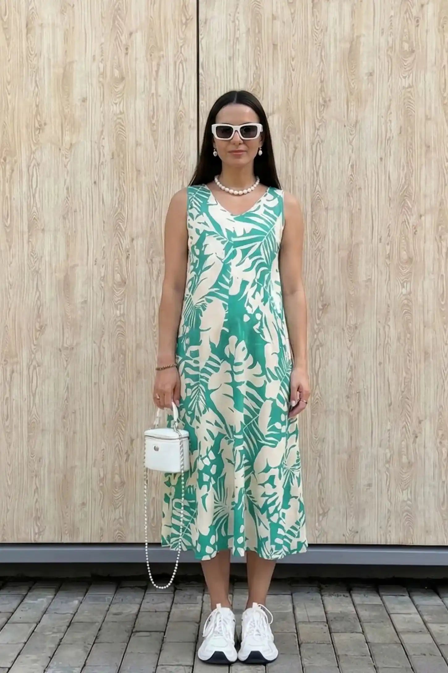 Tropical Print Sleeveless Midi Maternity Dress Tropical Print Sleeveless Midi Maternity Dress in Green featuring a bold palm print on a model in a casual setting, front view.