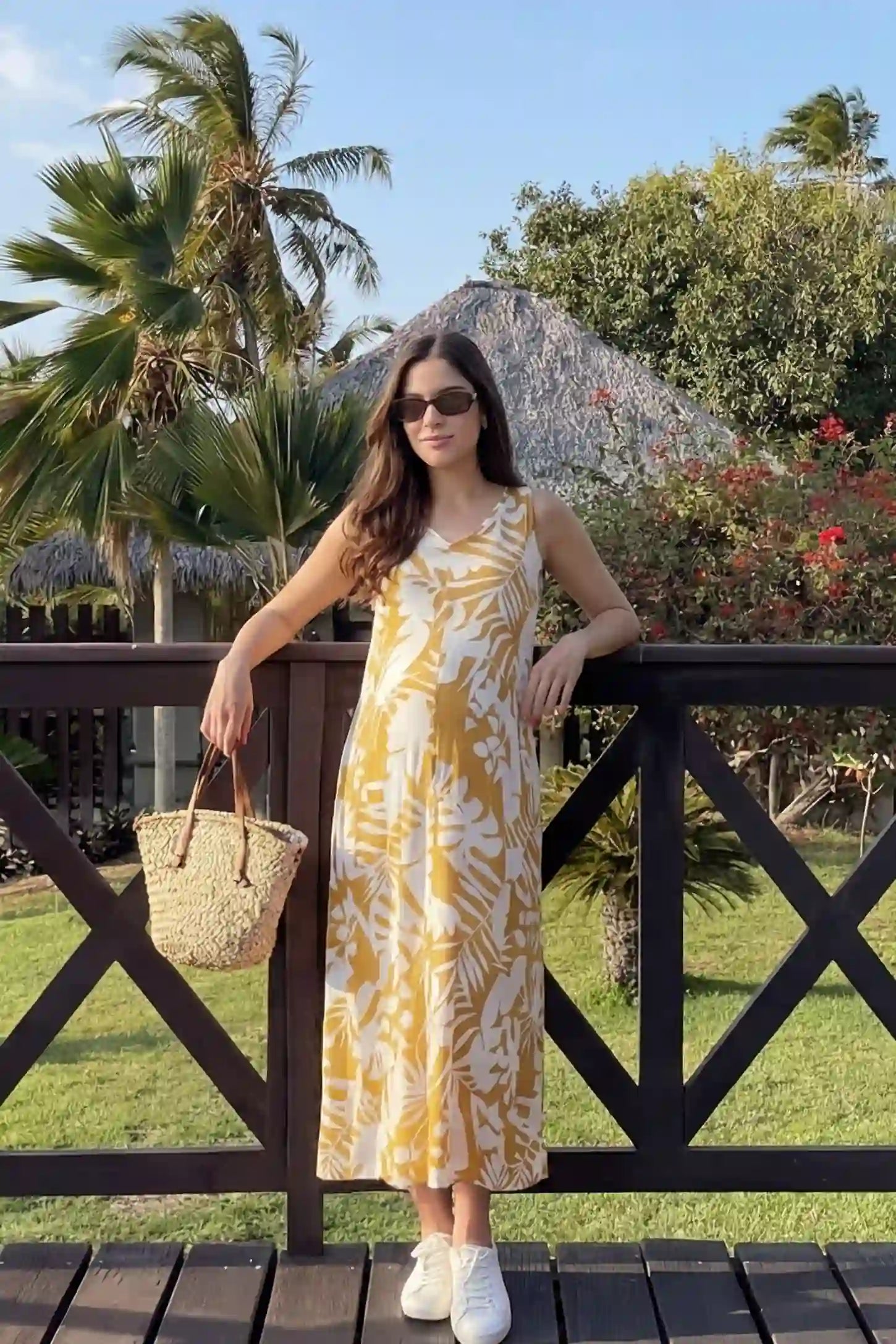 Tropical Print Sleeveless Midi Maternity Dress Tropical Print Sleeveless Midi Maternity Dress in Orange featuring a vibrant tropical pattern on a model in a garden setting, front view.