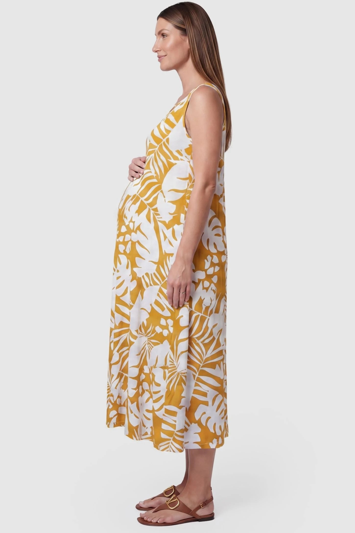 Tropical Print Sleeveless Midi Maternity Dress Tropical Print Sleeveless Midi Maternity Dress in Orange featuring a bump-friendly relaxed fit on a pregnant model, side view.