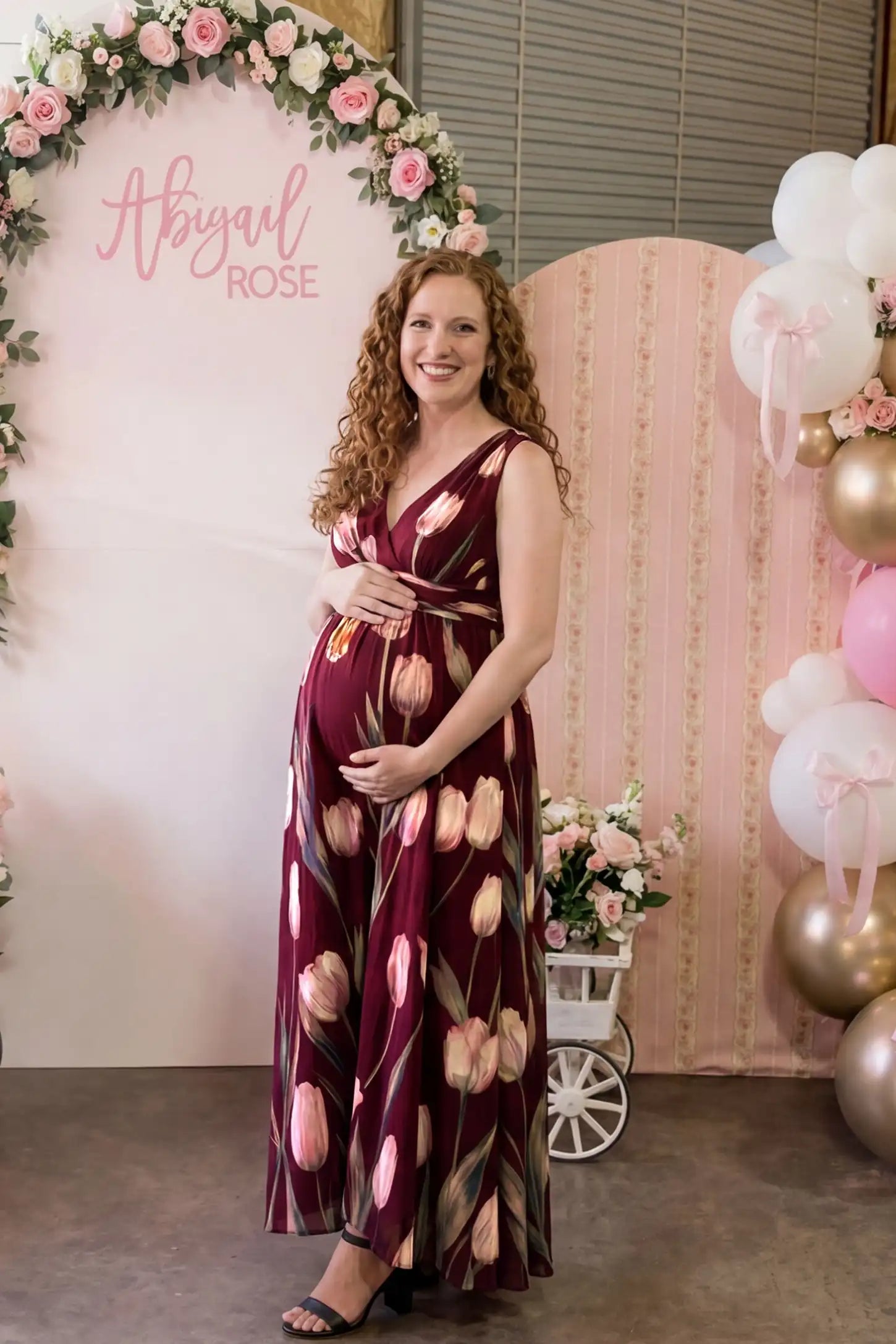 Tulip Print V-Neck Maxi Dress Tulip Print V-Neck Maxi Dress in Wine Red featuring a vibrant tulip floral print on a pregnant model, side view.