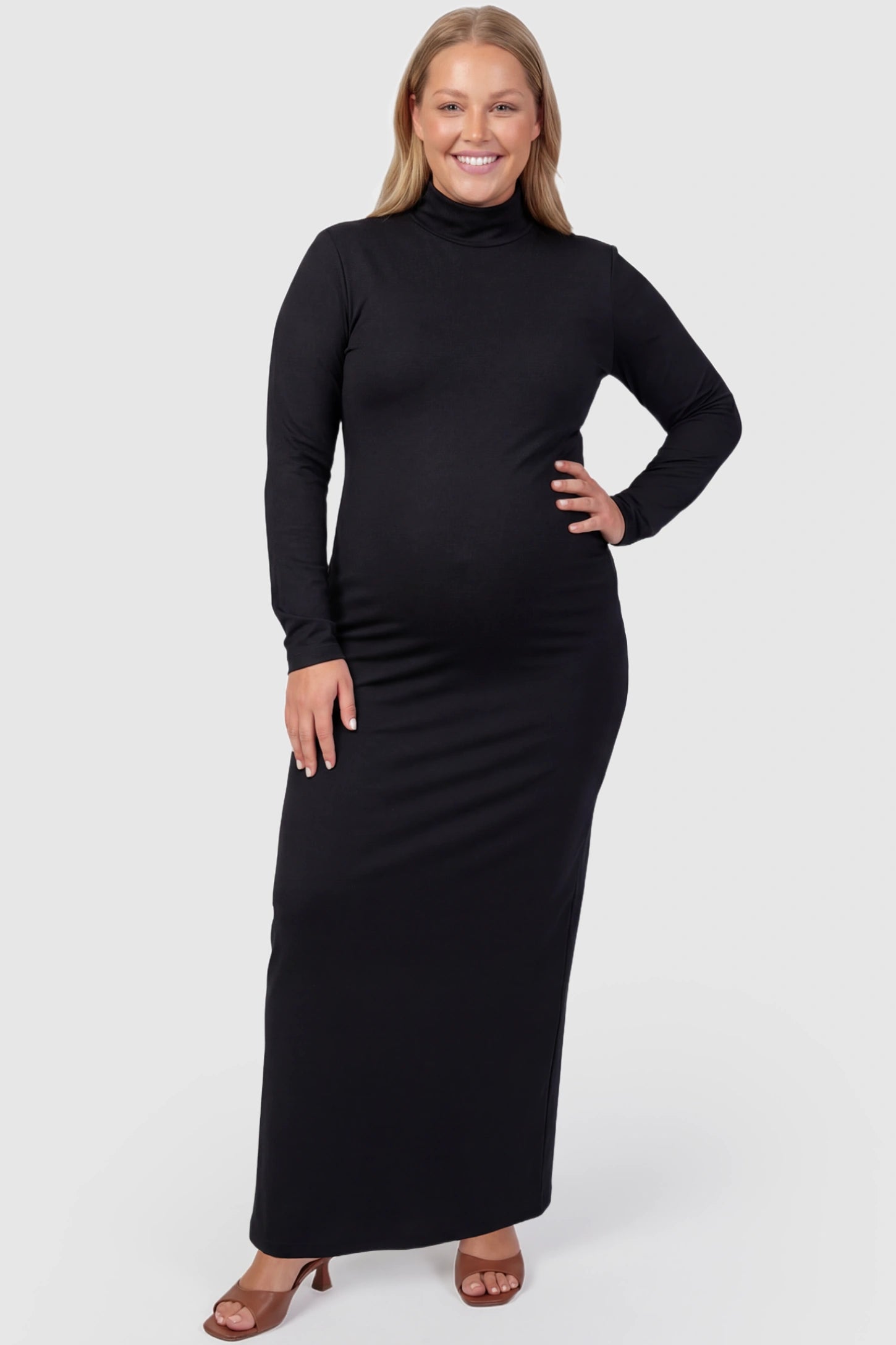 Turtle Neck Long Sleeve Maternity Maxi Dress Turtle Neck Long Sleeve Maternity Maxi Dress in Black featuring a turtleneck and long sleeves on a plus size pregnant model, front view.
