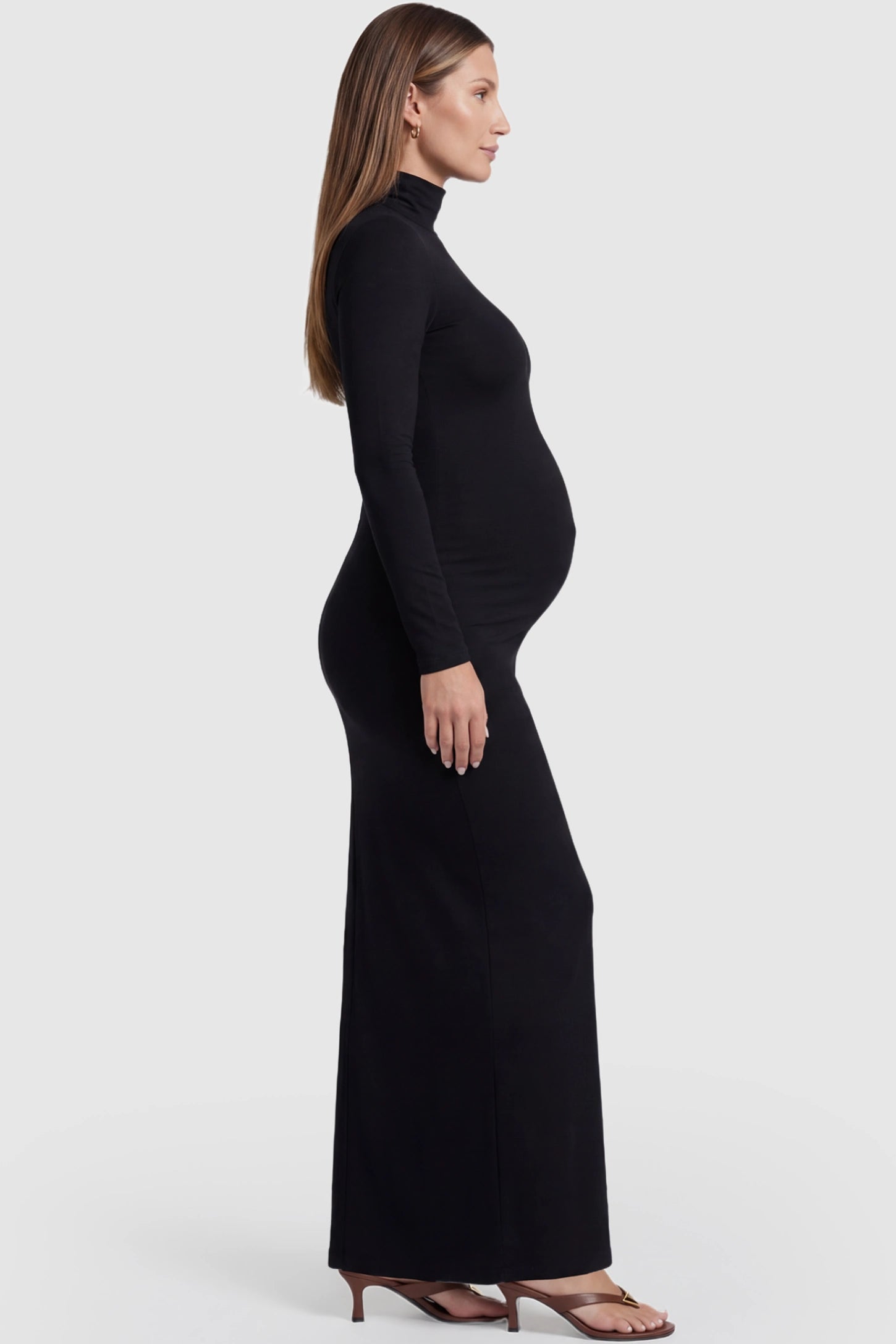 Turtle Neck Long Sleeve Maternity Maxi Dress Turtle Neck Long Sleeve Maternity Maxi Dress in Black featuring a turtleneck and long sleeves on a pregnant model, side view.