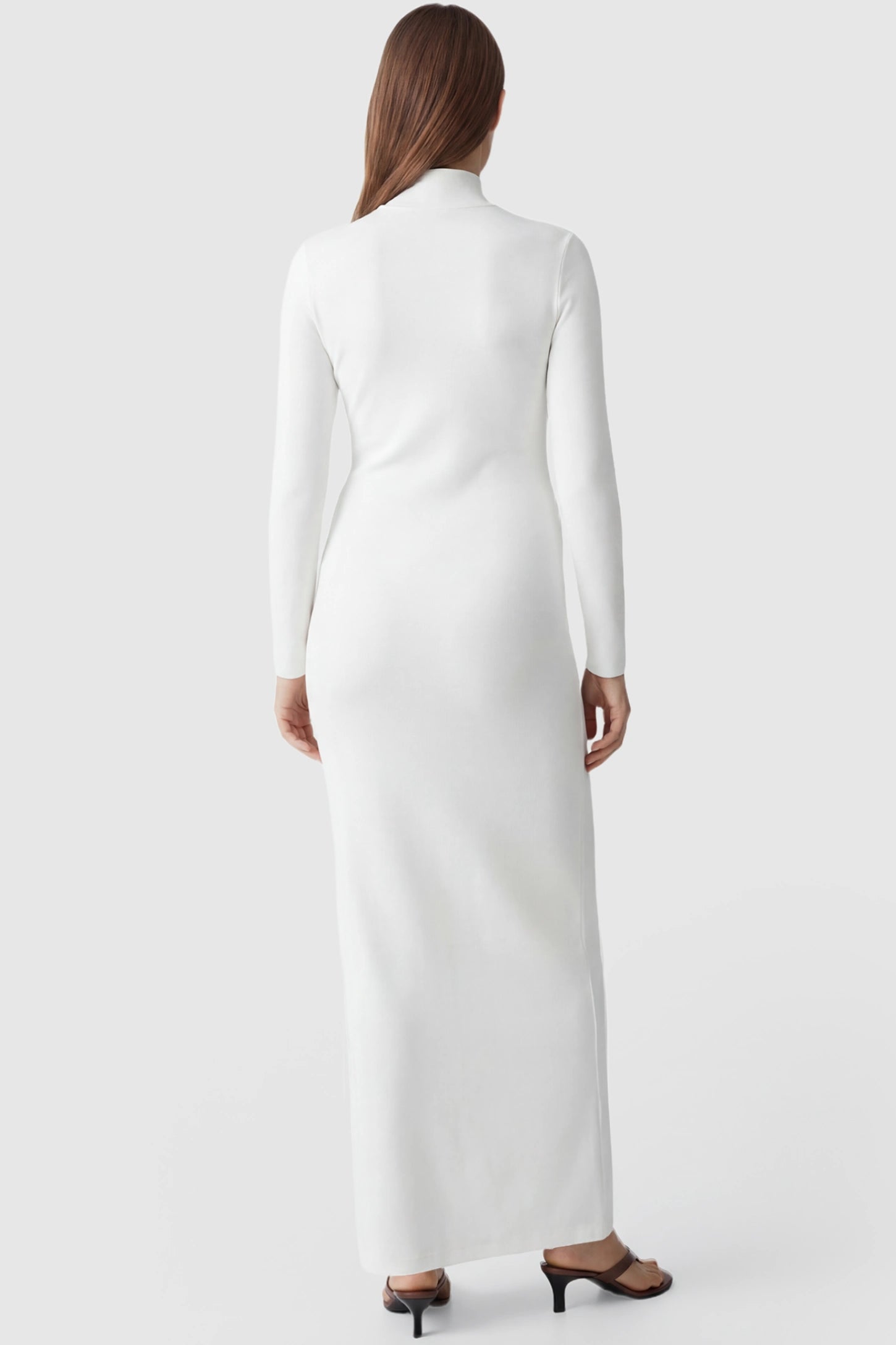 Turtle Neck Long Sleeve Maternity Maxi Dress Turtle Neck Long Sleeve Maternity Maxi Dress in White featuring a sleek floor-length silhouette and long sleeves on a pregnant model, back view.