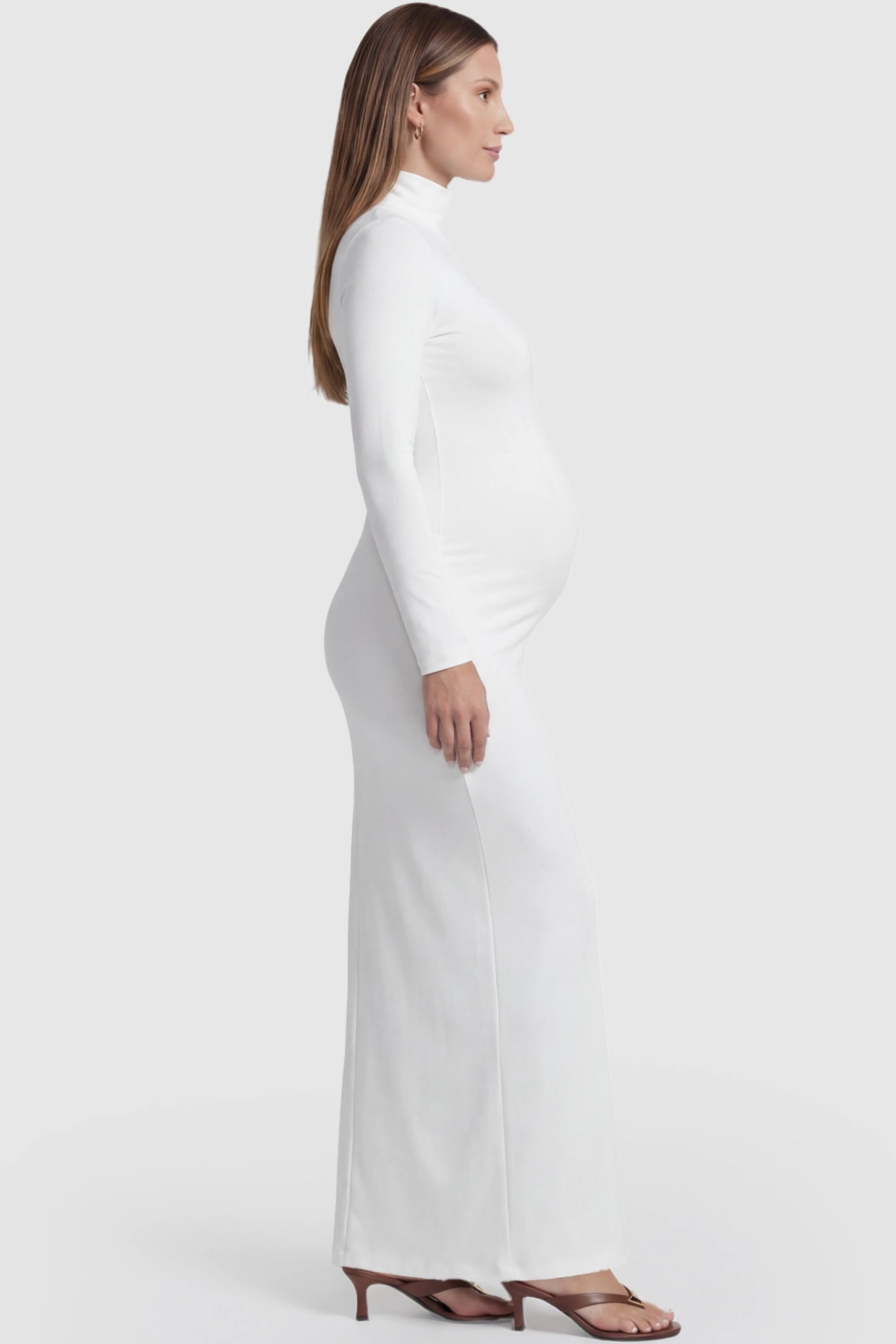Turtle Neck Long Sleeve Maternity Maxi Dress Turtle Neck Long Sleeve Maternity Maxi Dress in White featuring a turtleneck and long sleeves on a pregnant model, side view.