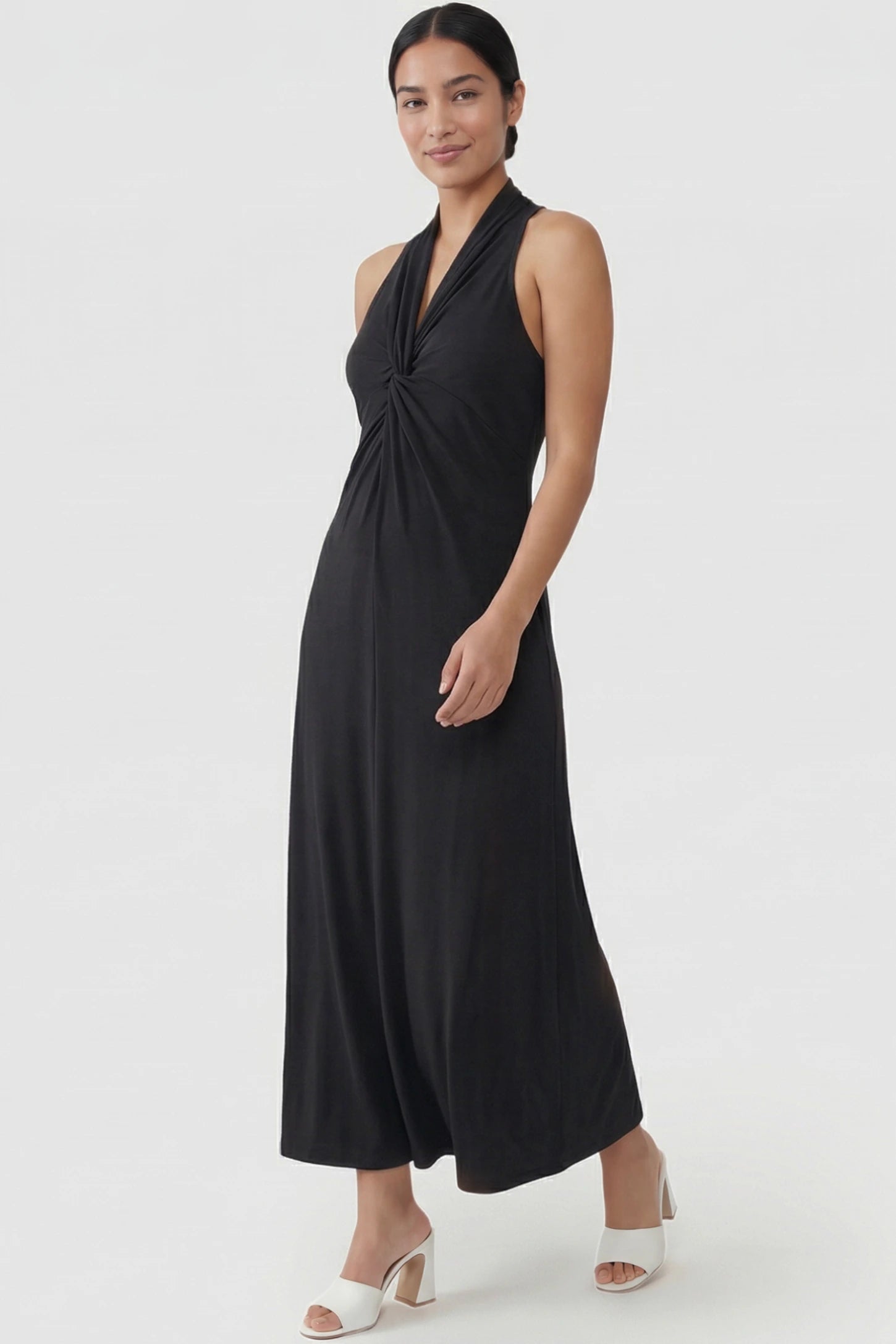 Twist Front Halter Neck Maternity Maxi Dress Twist Front Halter Neck Maternity Maxi Dress in Black featuring knot detail, sleeveless, A-line silhouette on a postpartum model, front view.
