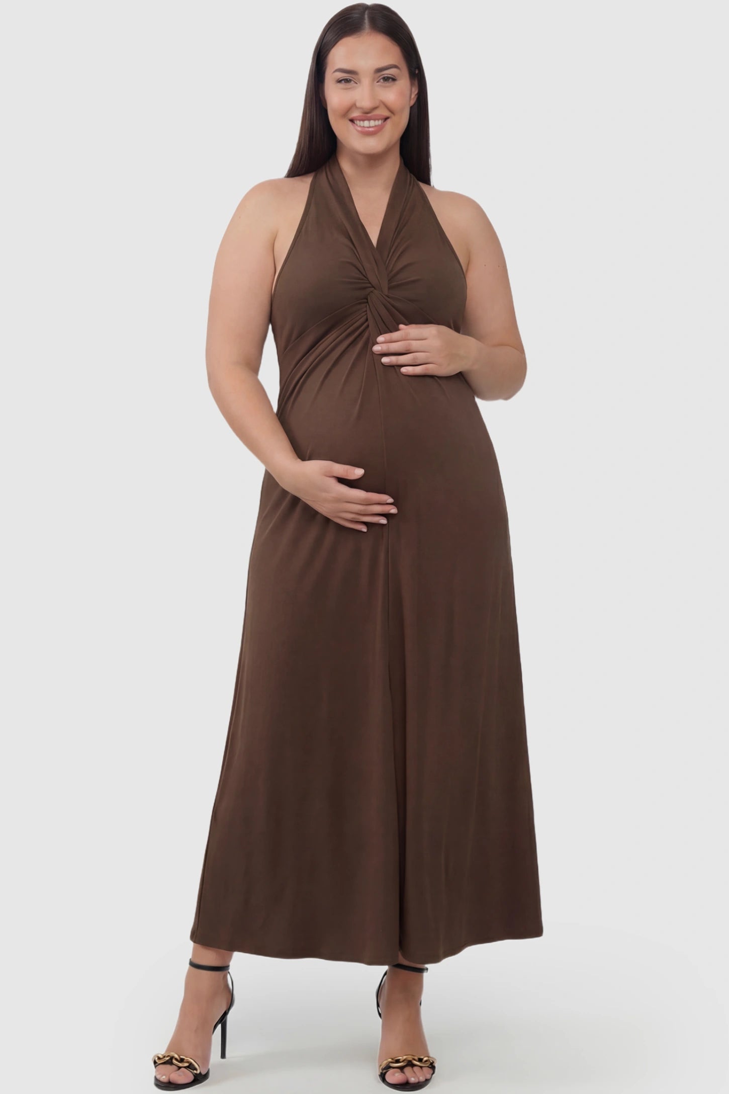 Twist Front Halter Neck Maternity Maxi Dress Twist Front Halter Neck Maternity Maxi Dress in Coffee featuring knot detail, sleeveless, A-line silhouette on a plus size pregnant model, front view.