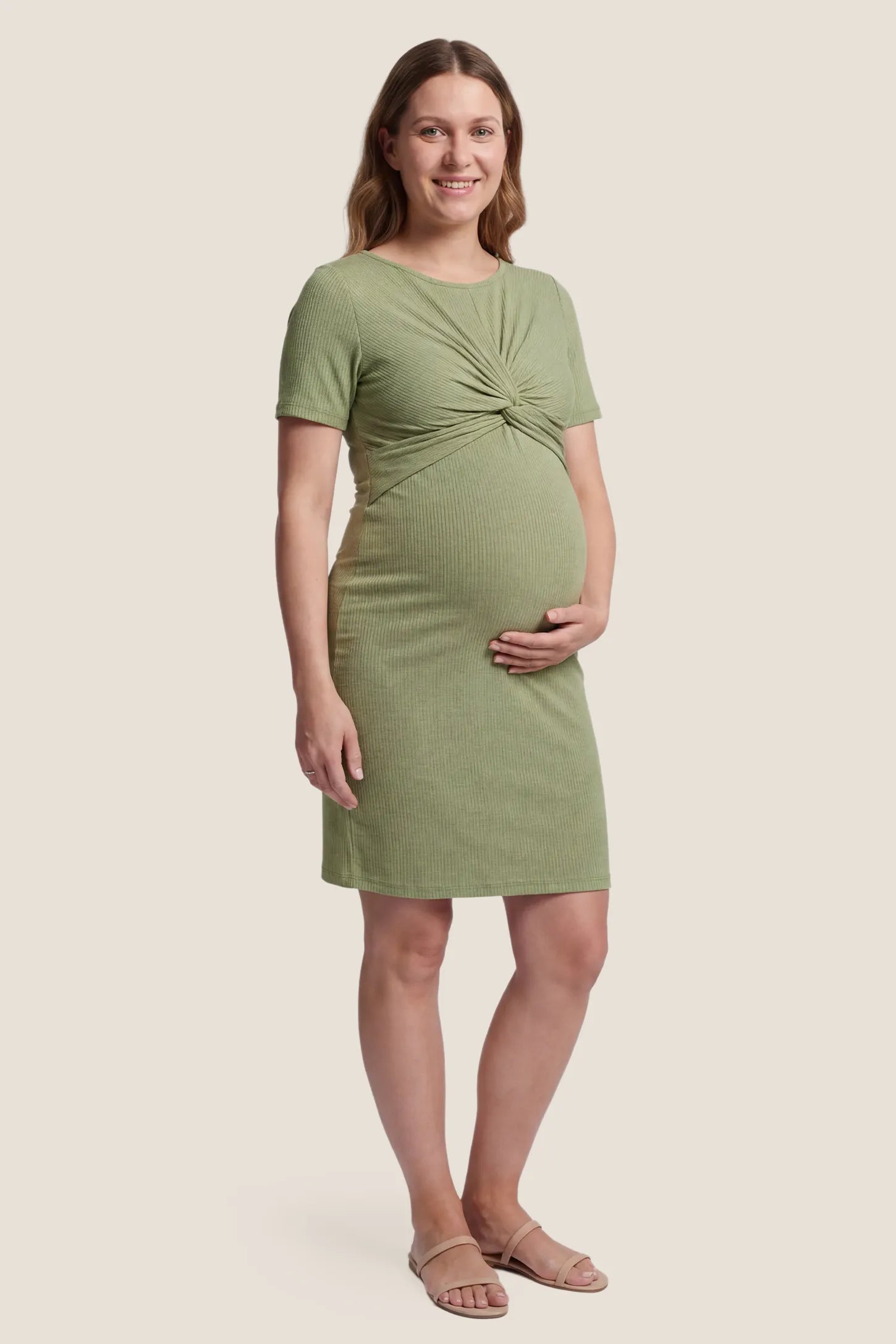 Twist Front Round Neck Short Sleeve Maternity Short Dress Twist Front Round Neck Maternity Short Dress in green featuring side ruched panels on a plus size postpartum model, front view.