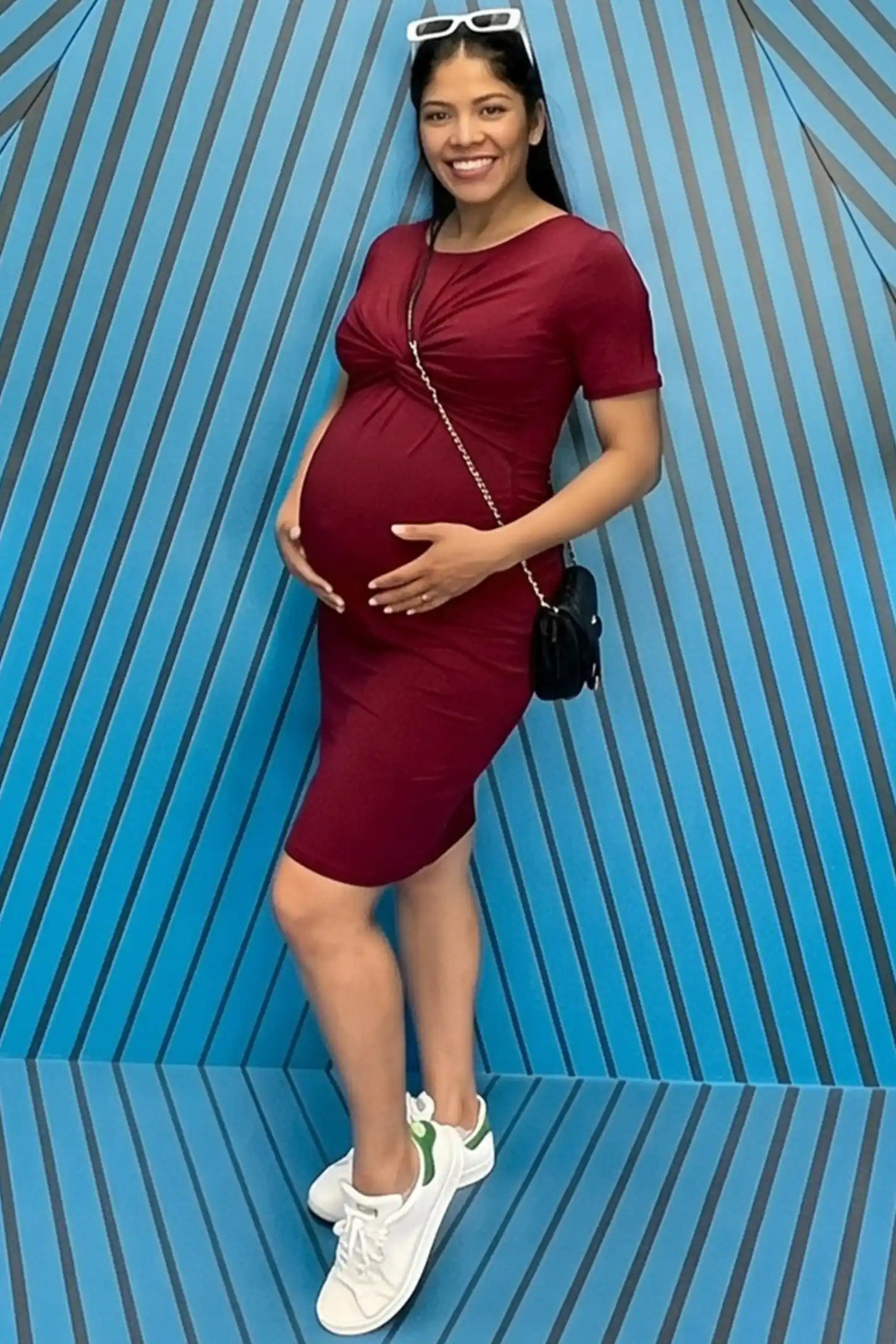 Twist Front Round Neck Short Sleeve Maternity Short Dress Twist Front Round Neck Maternity Short Dress in wine red featuring side ruched panels on a pregnant woman in outdoor setting, front view.