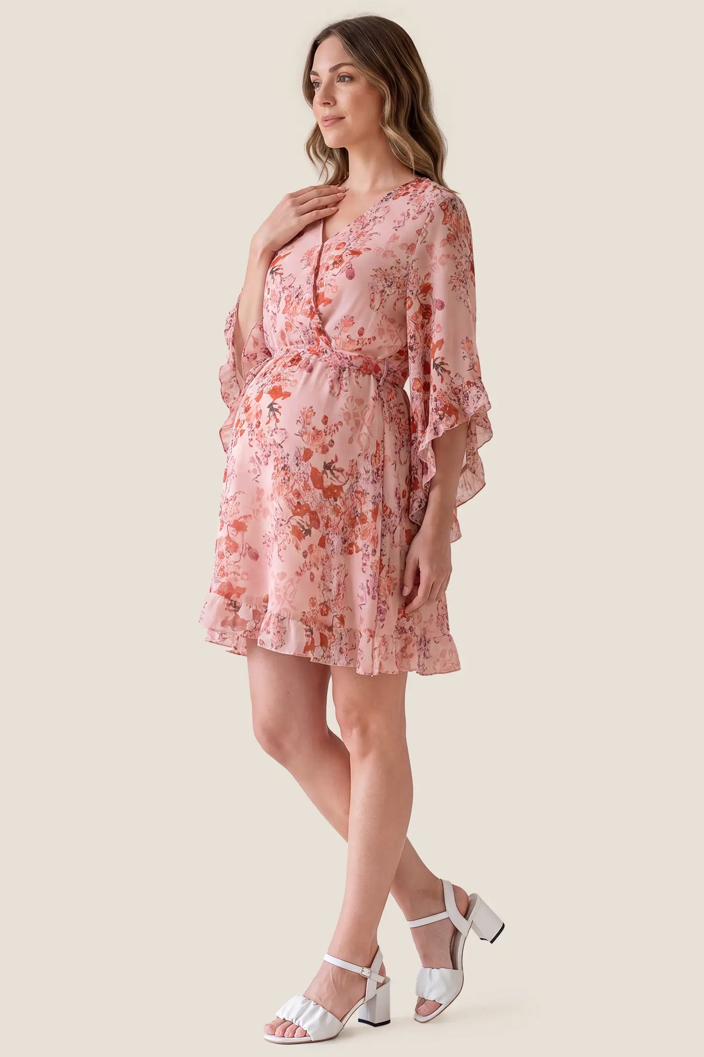 V-Neck Bell Sleeve Long Sleeve Maternity Dress V-Neck Bell Sleeve Long Sleeve Maternity Dress in Blush Floral accommodating a growing bump on a pregnant model, studio side view.