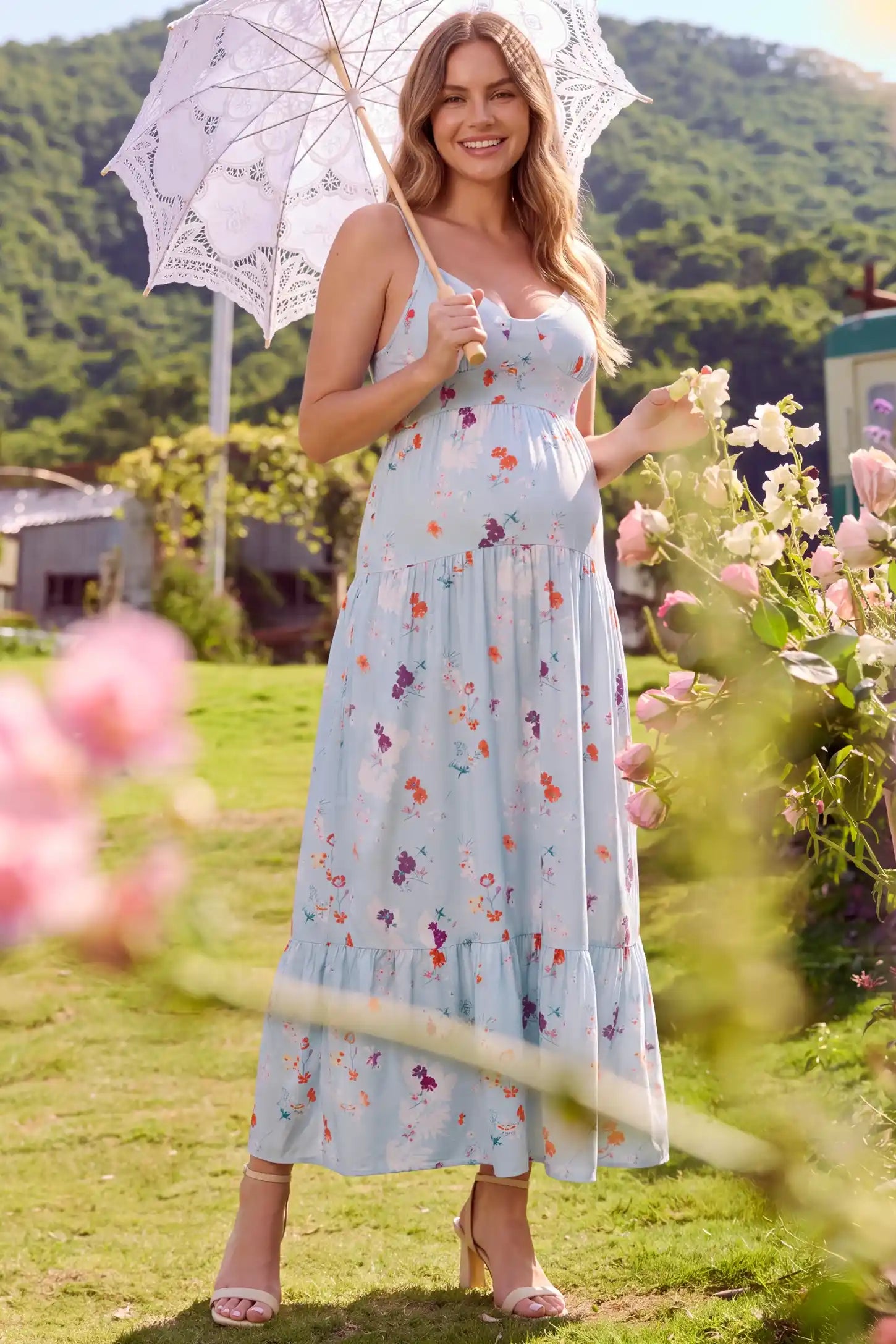 V-Neck Open Back Maternity Maxi Dress V-Neck Open Back Maternity Maxi Dress in Light Blue Floral featuring a V-neckline and flowy tiered skirt on a pregnant model, lifestyle front view.
