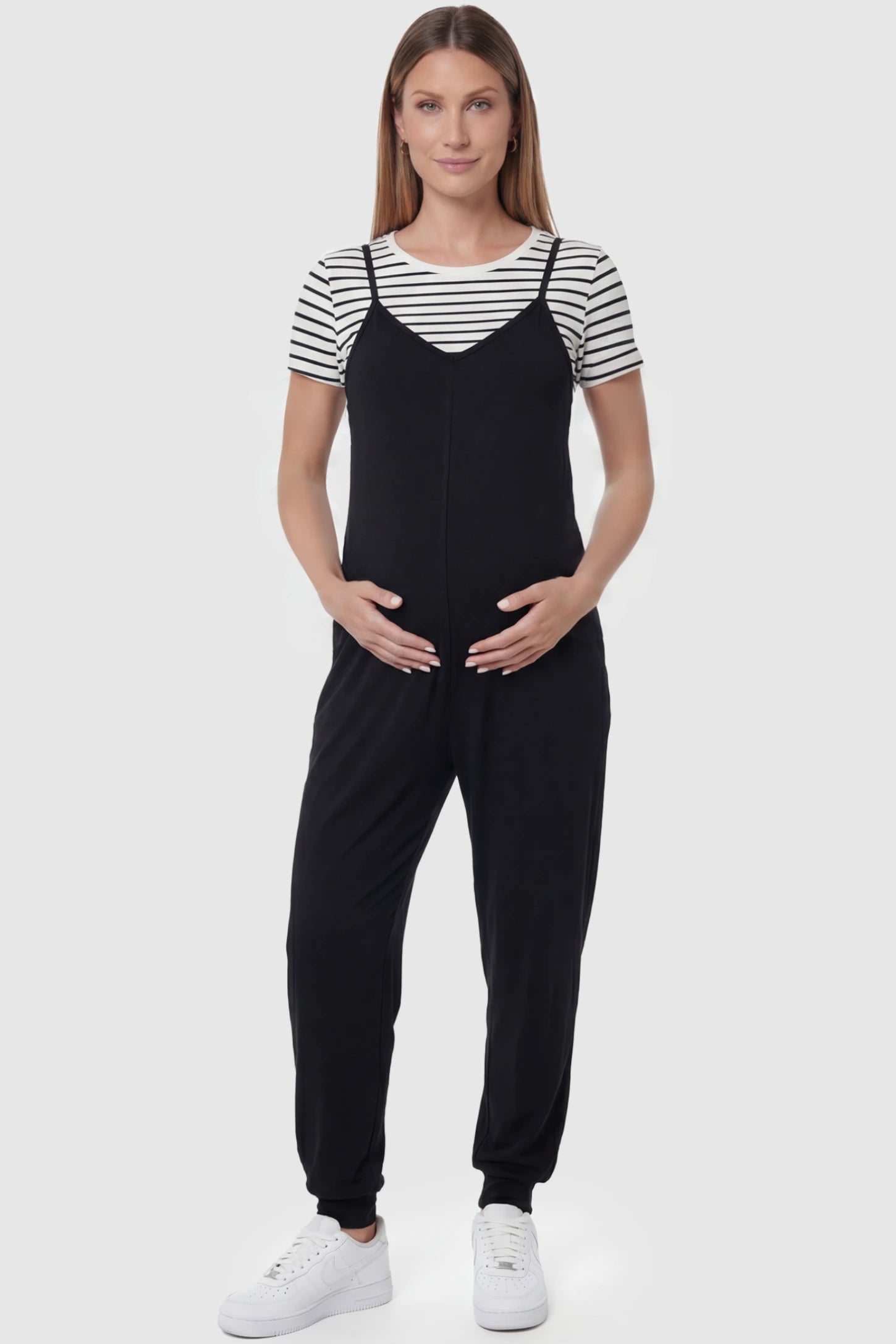 V-Neck Pocketed Maternity Jogger Jumpsuit in Black featuring cotton-spandex jersey and side pockets on a pregnant model, front view.