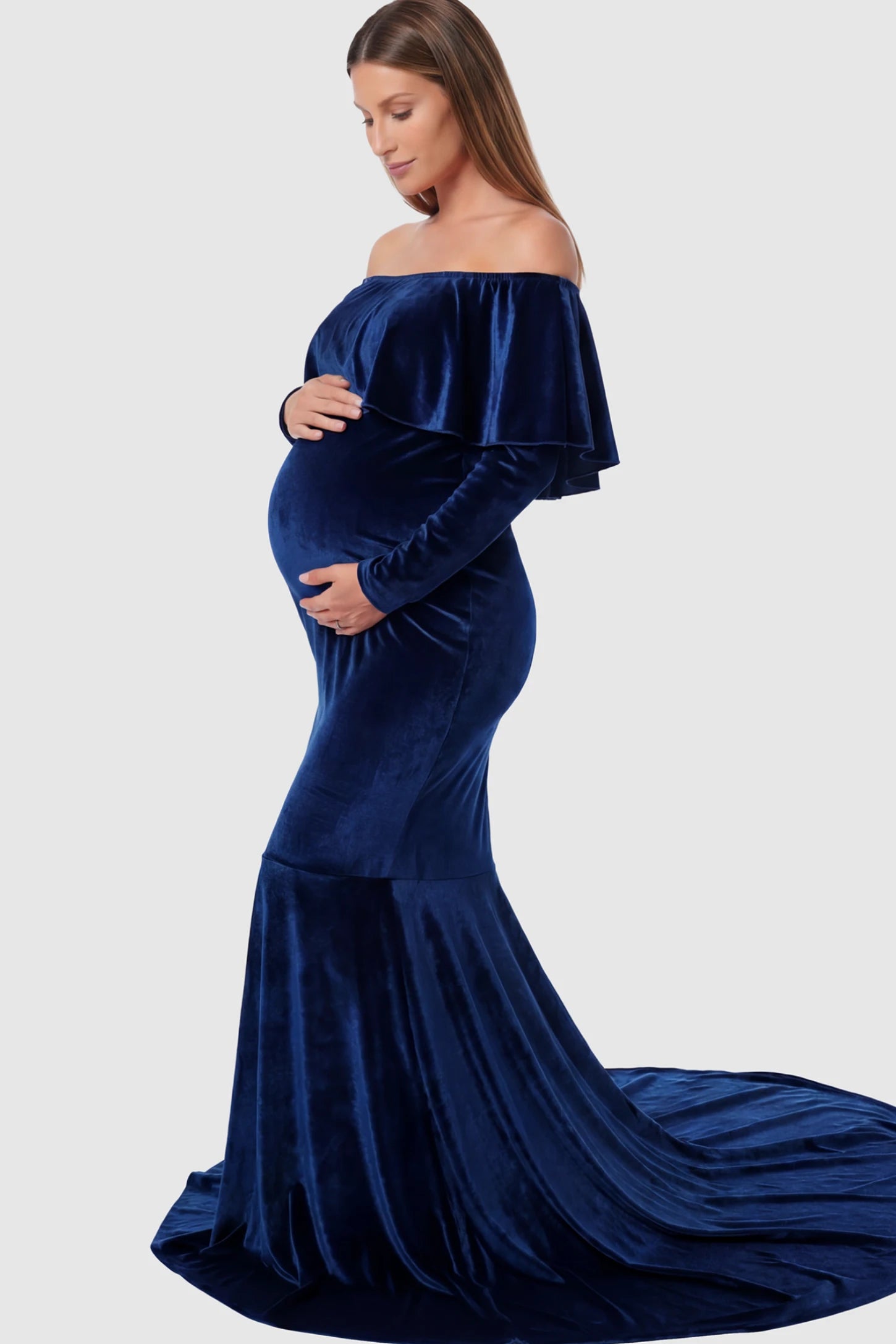 Velvet Off Shoulder Long Sleeve Maternity Mermaid Gown Velvet Off-the-Shoulder Maternity Mermaid Gown in Dark Blue featuring a ruffled neckline and long sleeves on a pregnant model showing side.