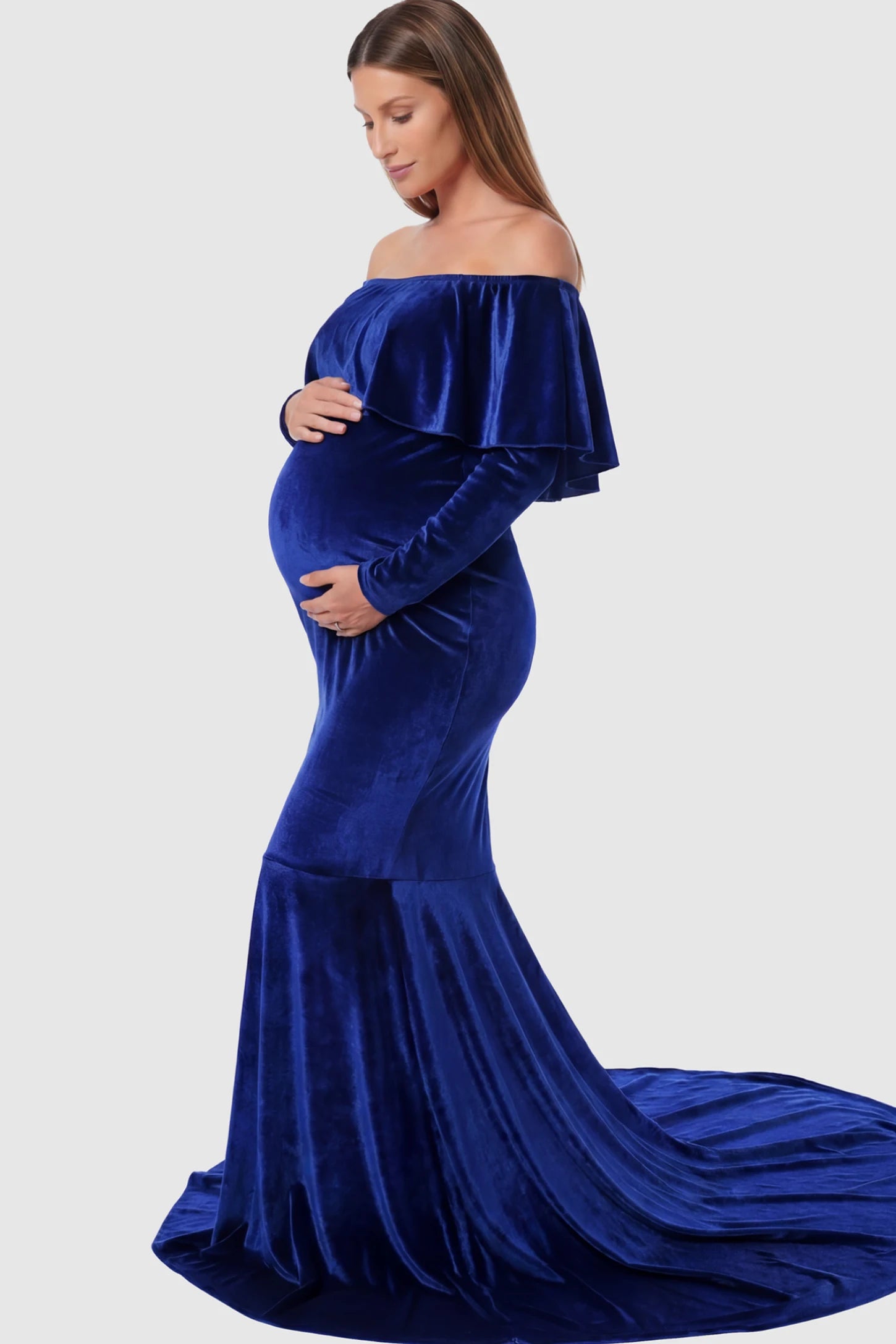 Velvet Off Shoulder Long Sleeve Maternity Mermaid Gown Velvet Off-the-Shoulder Maternity Mermaid Gown in Rainbow Blue featuring a ruffled neckline and long sleeves on a pregnant model showing side.