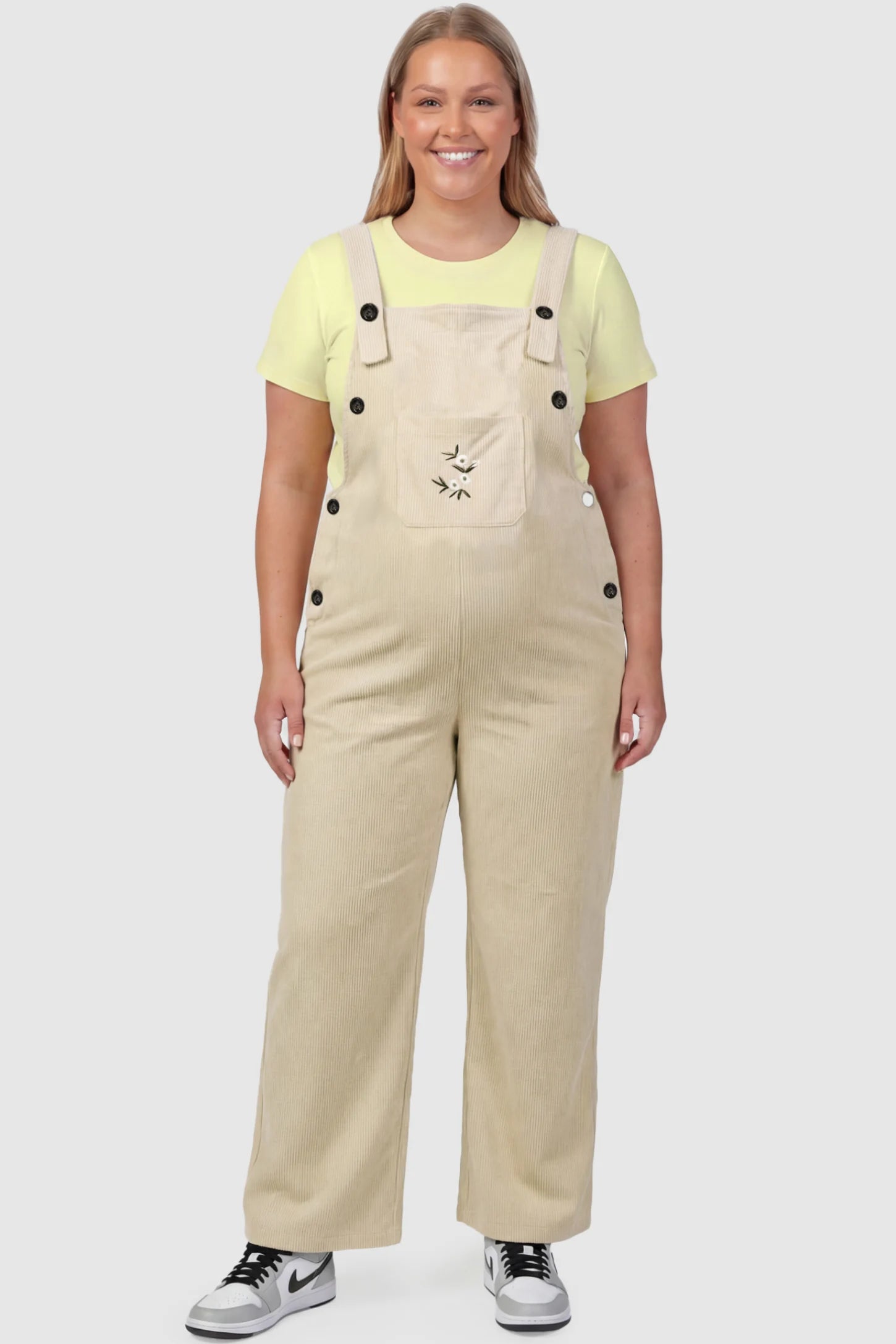 Adjustable Strap Wide-Leg Corduroy Maternity Overalls Floral Embroidered Wide-Leg Maternity Overalls in apricot featuring adjustable straps on a plus size pregnant model, front view.